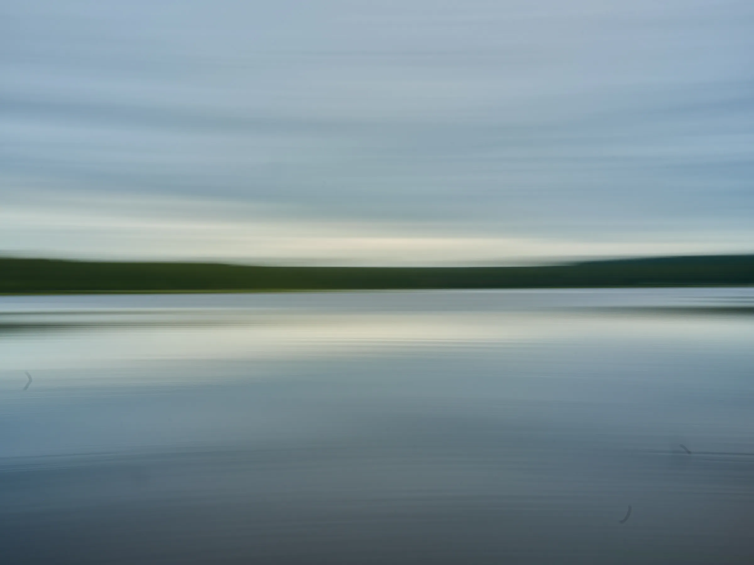 Lake with a soft horizon in evening light, calmed by a long exposure