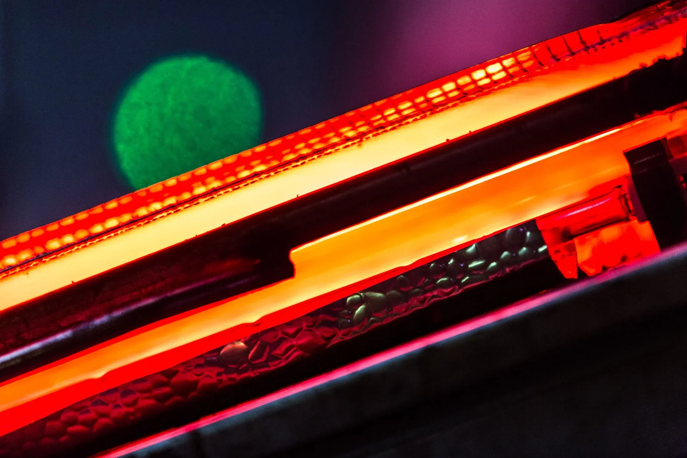 Detail einer glühenden Maschine, rotorange leuchtendes Material in der Fertigung bei Faist, vorhandenes Licht