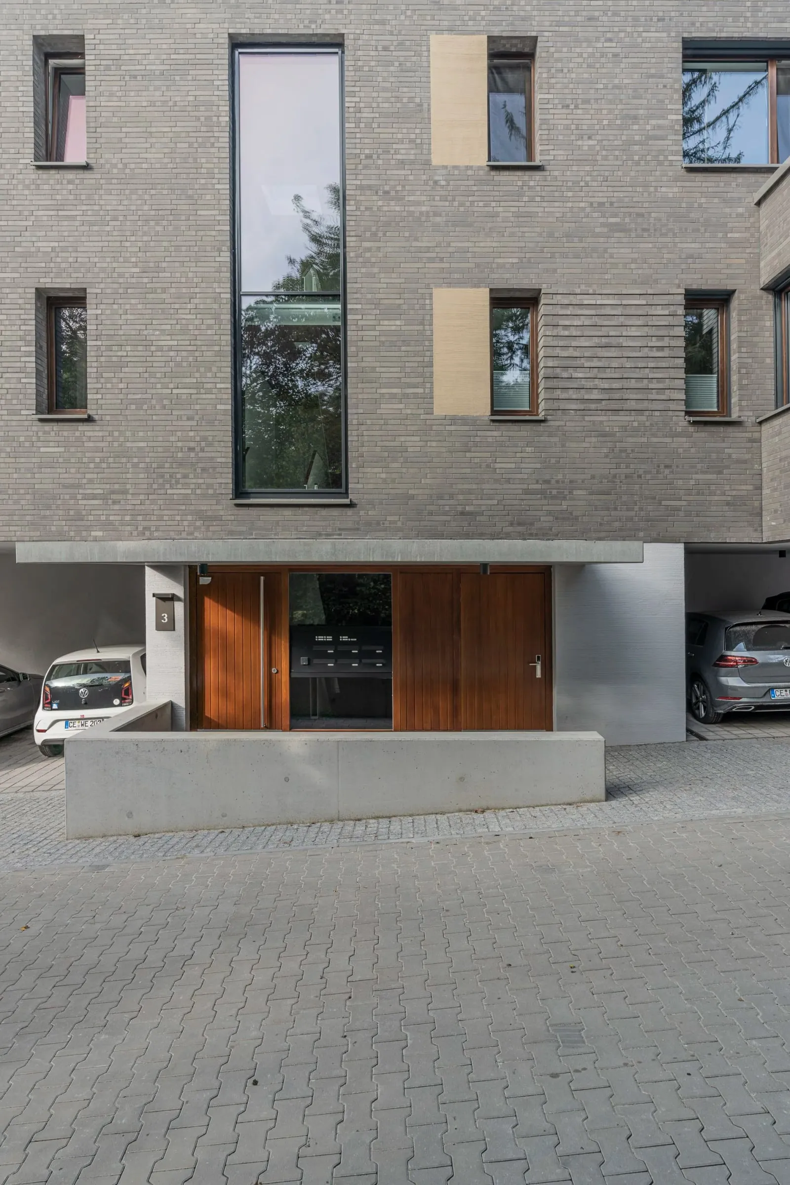Außenaufnahme der Klinkerfassade eines Wohnhauses von bwp Architekten, Holzeingangstür und überdachte Durchfahrt, Bodenperspektive
