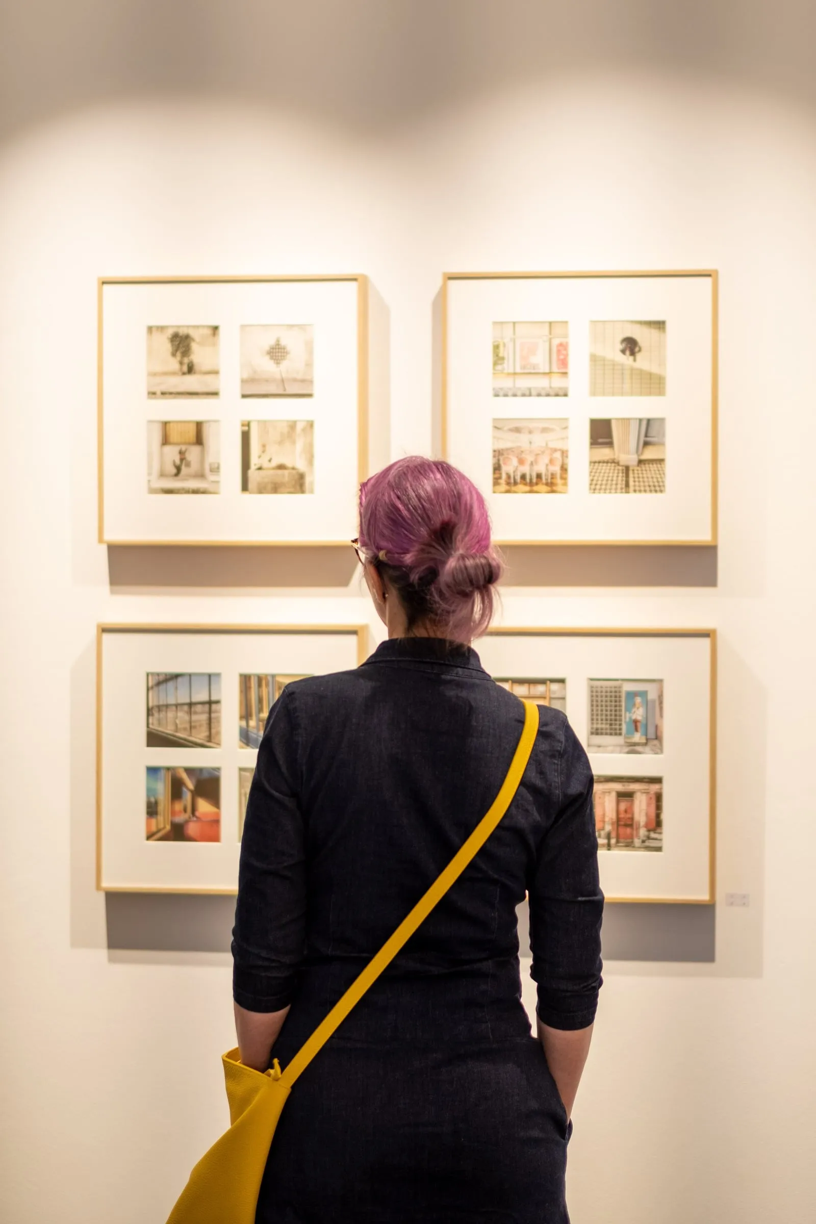 Besucherin mit pinkfarbenem Haar betrachtet vier gerahmte Fotografien der Reihe Hidden Places an der Wand