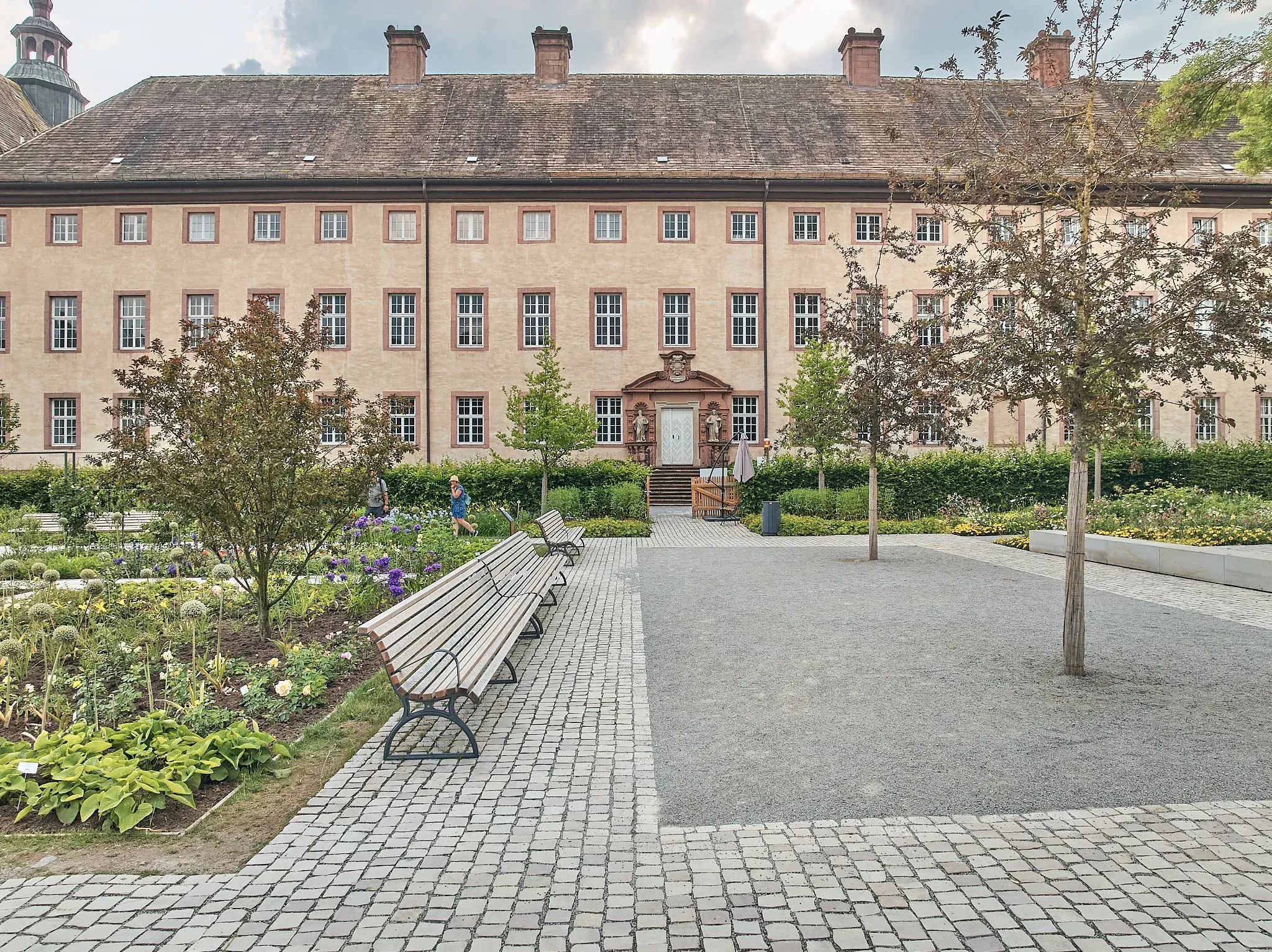 Remtergarten in Höxter, gepflasterter Weg mit Holzbänken vor dem historischen Gebäude, neue Pflanzbeete am Rand