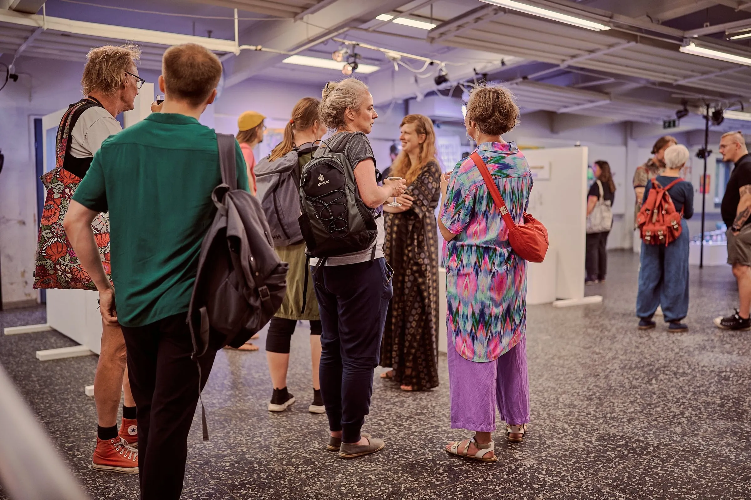 Besucherinnen und Besucher stehen in Gruppen zwischen Stellwänden im hellen Ausstellungsraum