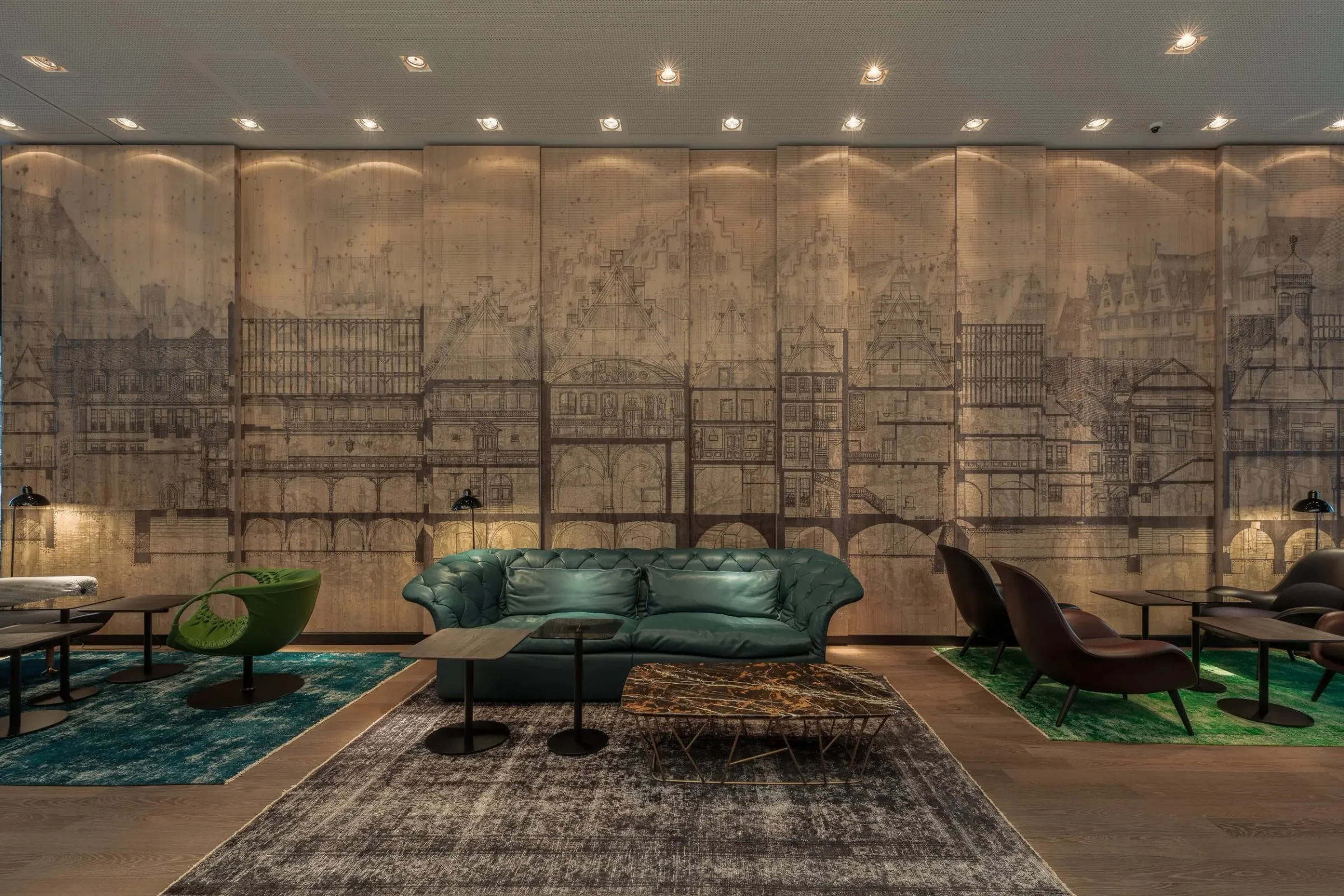 Lobby des Motel One mit grünem Ledersofa, Sesseln und großer Wandzeichnung von Frankfurter Häuserfassaden im Hintergrund