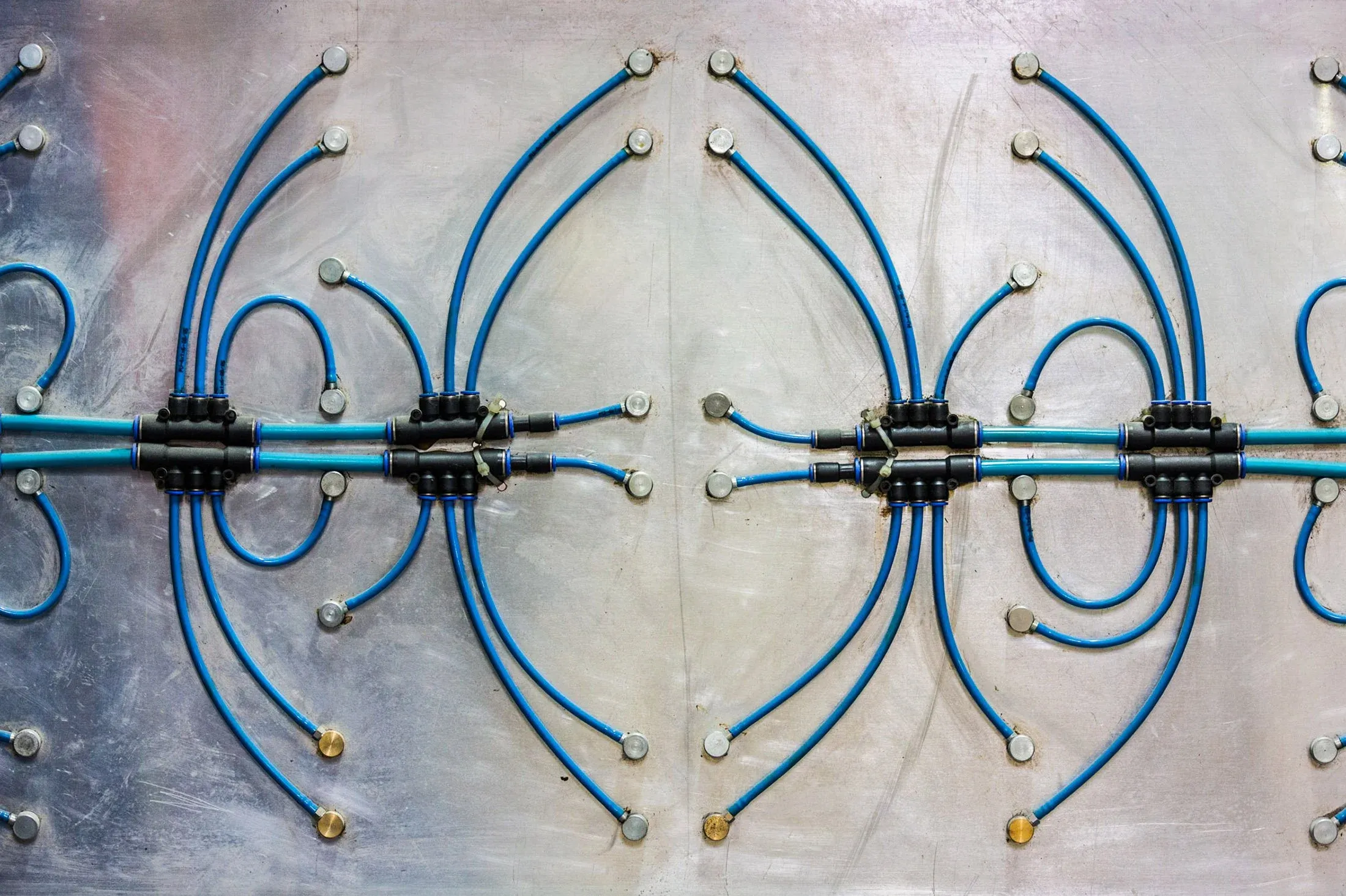 Metallplatte mit blauen Kabeln und schwarzen Steckverbindern, symmetrisch verschraubt, Detail aus der Produktion