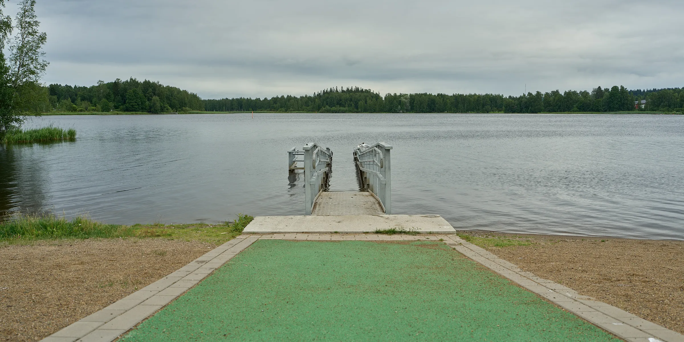 Double bathing jetty with a green runway leading into a still lake
