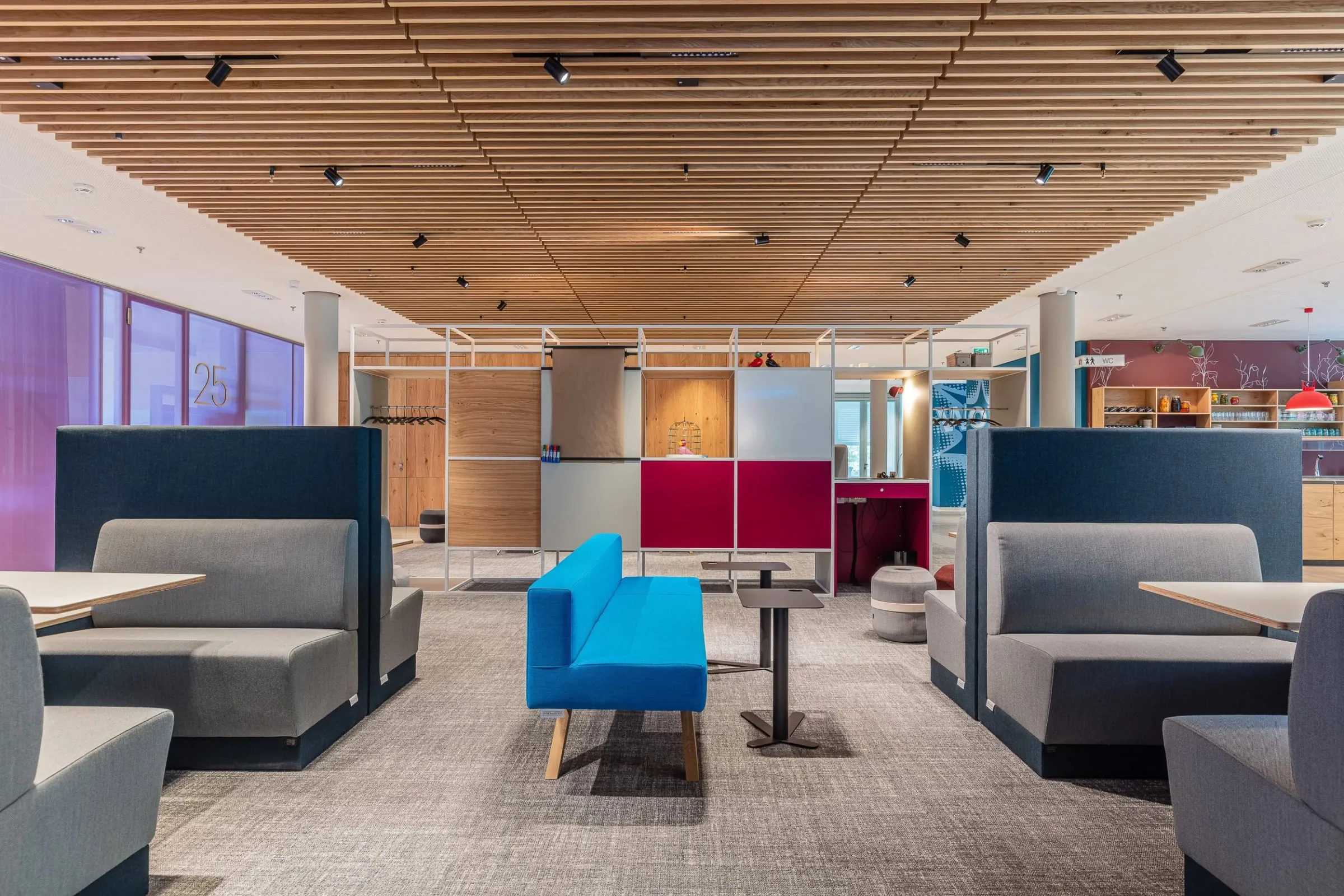 Lounge mit gepolsterten Sitznischen, blauem Sofa und Holzdecke, Rückzugsbereich der offenen Arbeitswelt