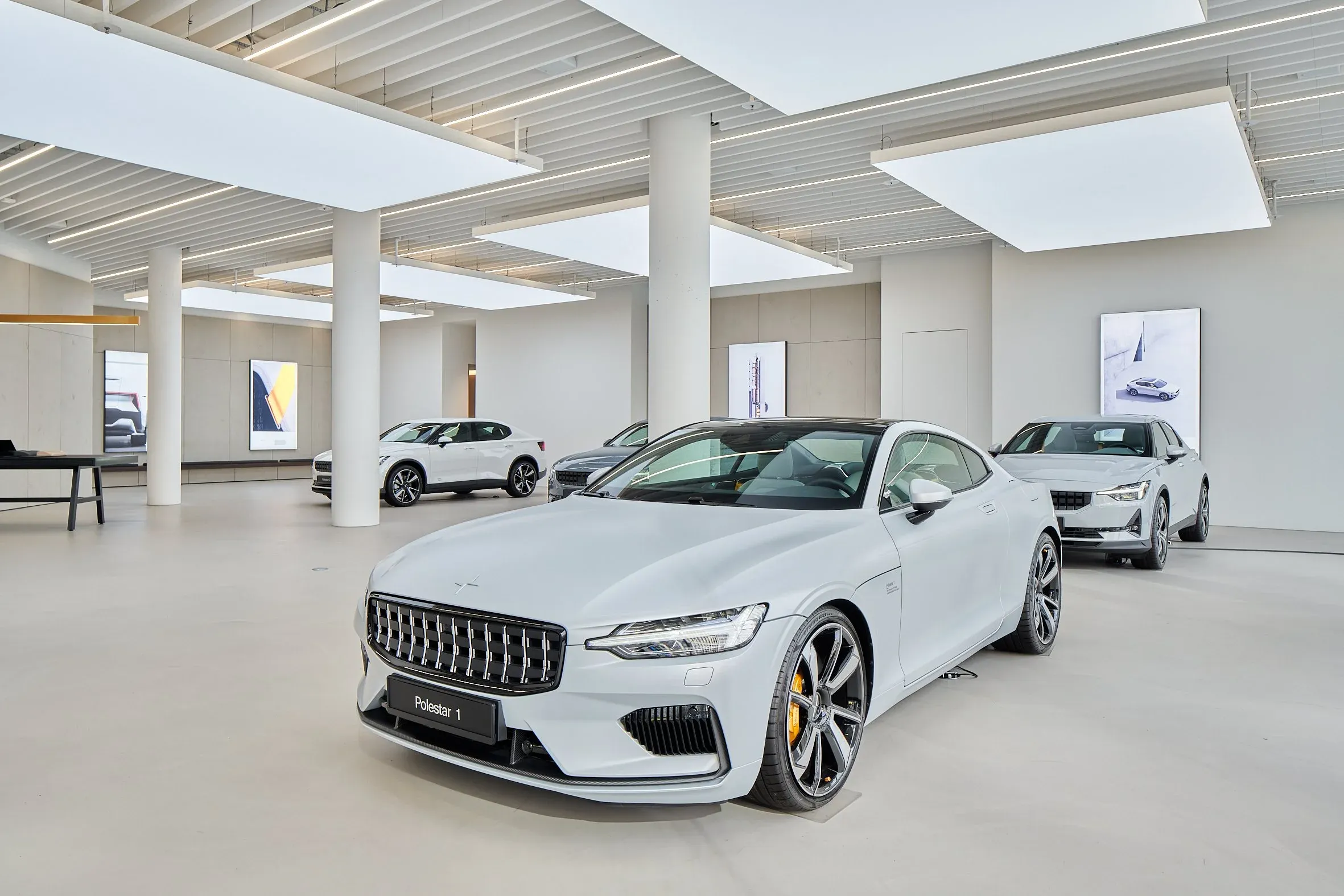 Innenraum des Showrooms, mehrere Polestar zwischen Säulen, weißer Polestar 1 im Vordergrund, helles Deckenlicht