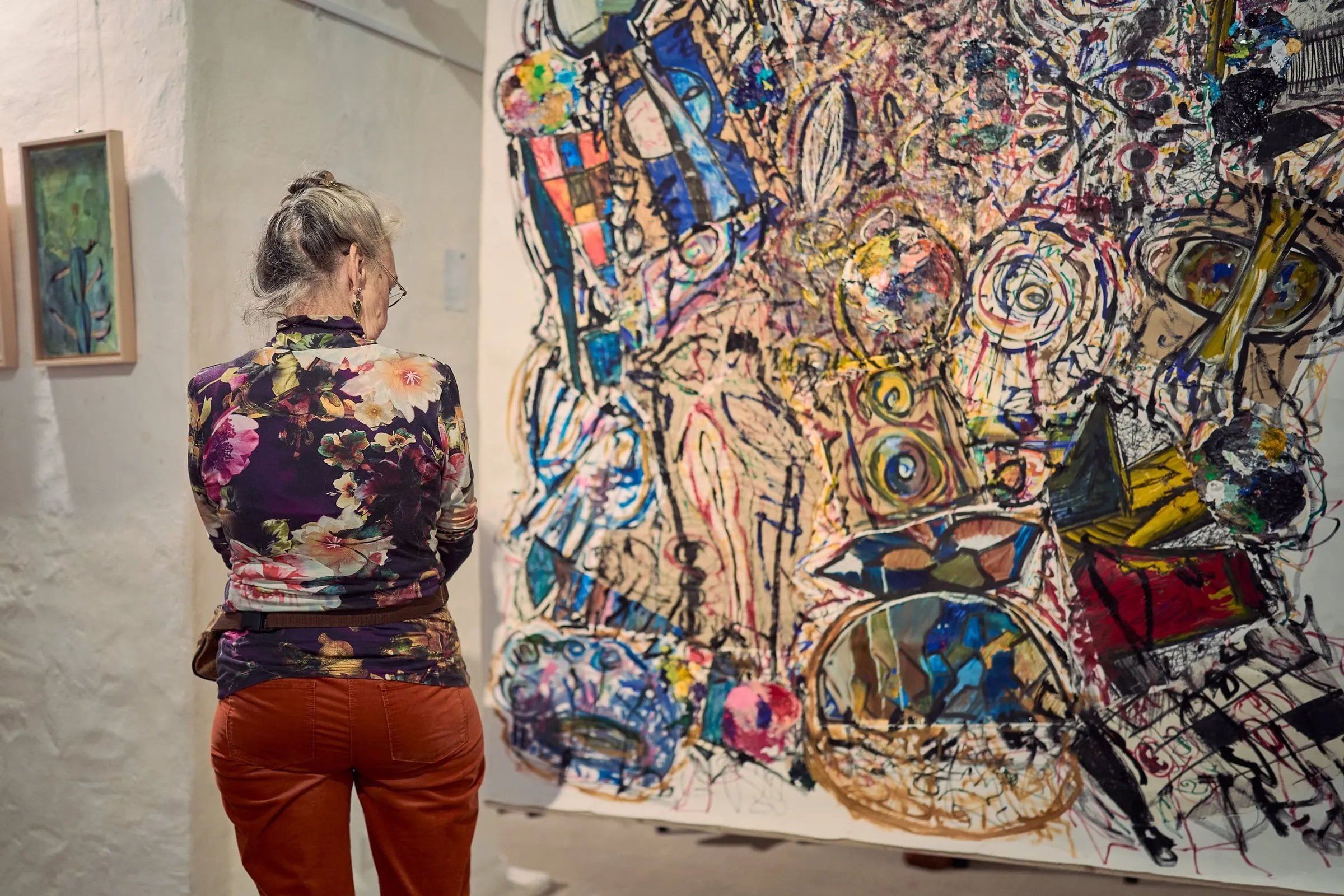 Frau von hinten betrachtet ein großes, dicht gezeichnetes Werk in der Ausstellung