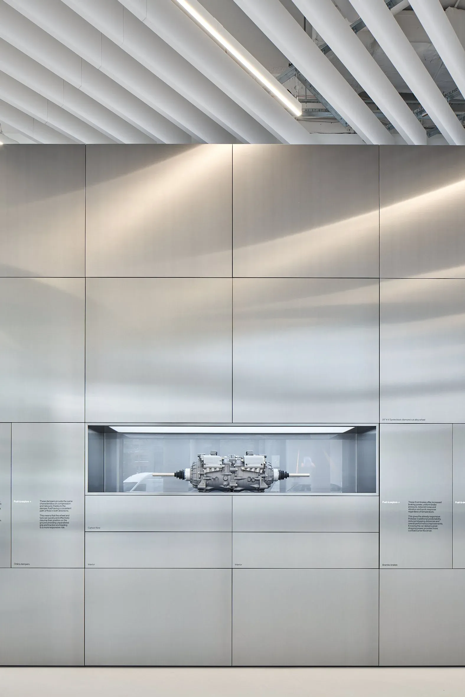 Innenraum, Detail einer Materialwand aus Metallpaneelen mit Antriebseinheit in beleuchteter Vitrine