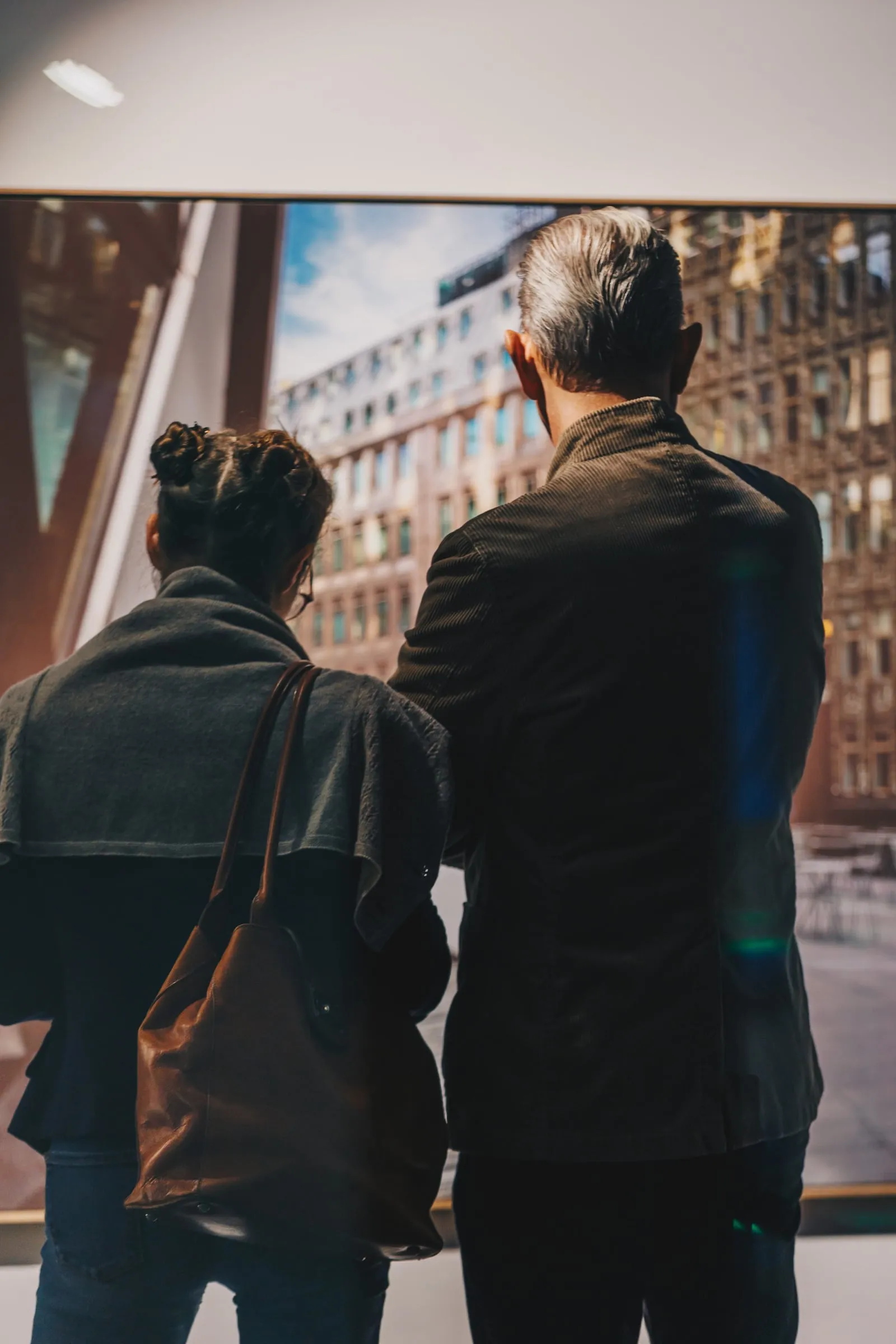 Zwei Personen von hinten vor einer großformatigen gerahmten Fotografie städtischer Häuserfassaden
