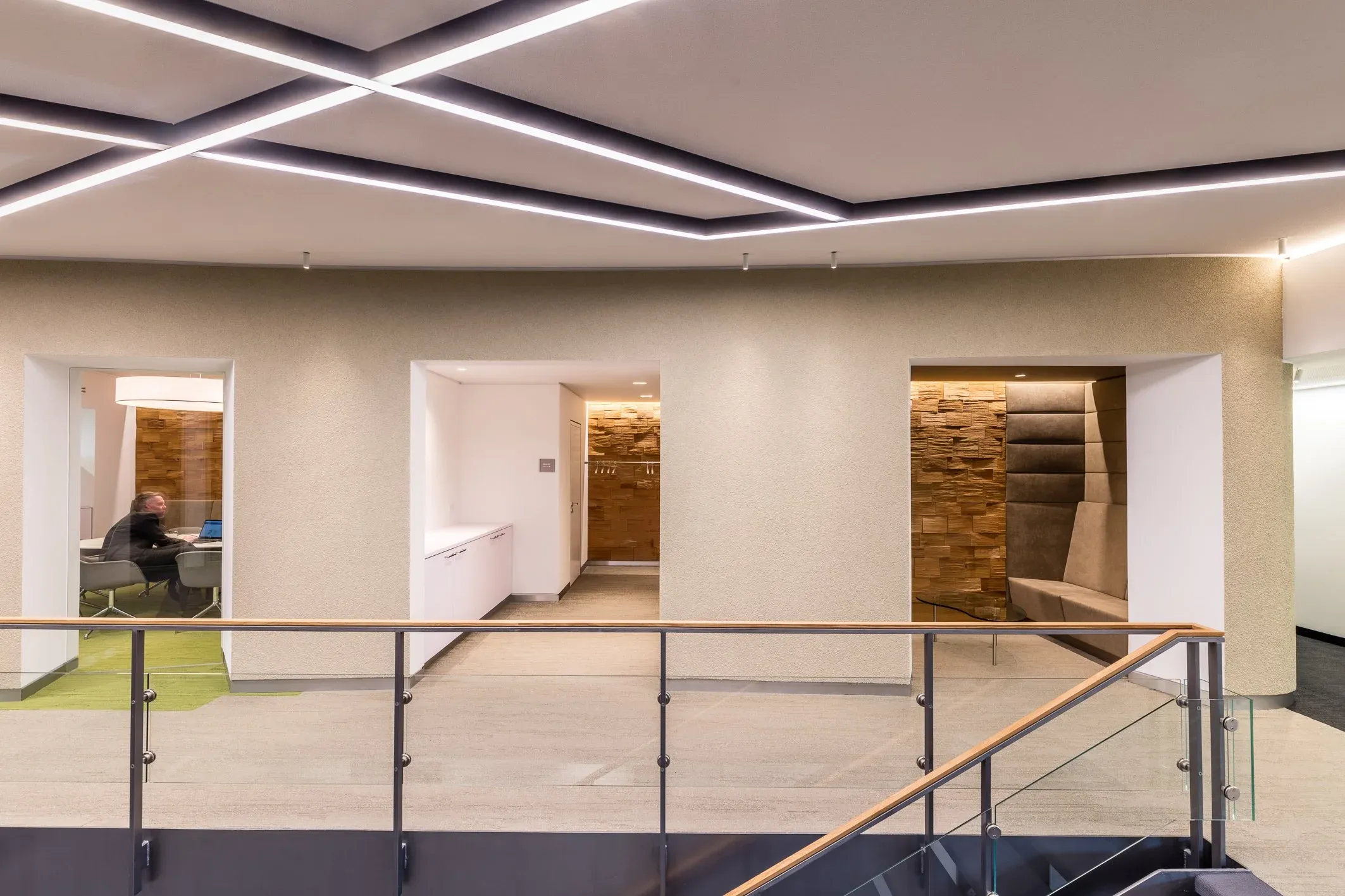 Innenaufnahme eines Foyers mit Galeriebrüstung, Lichtbändern an der Decke und Durchgängen zu hellen Räumen