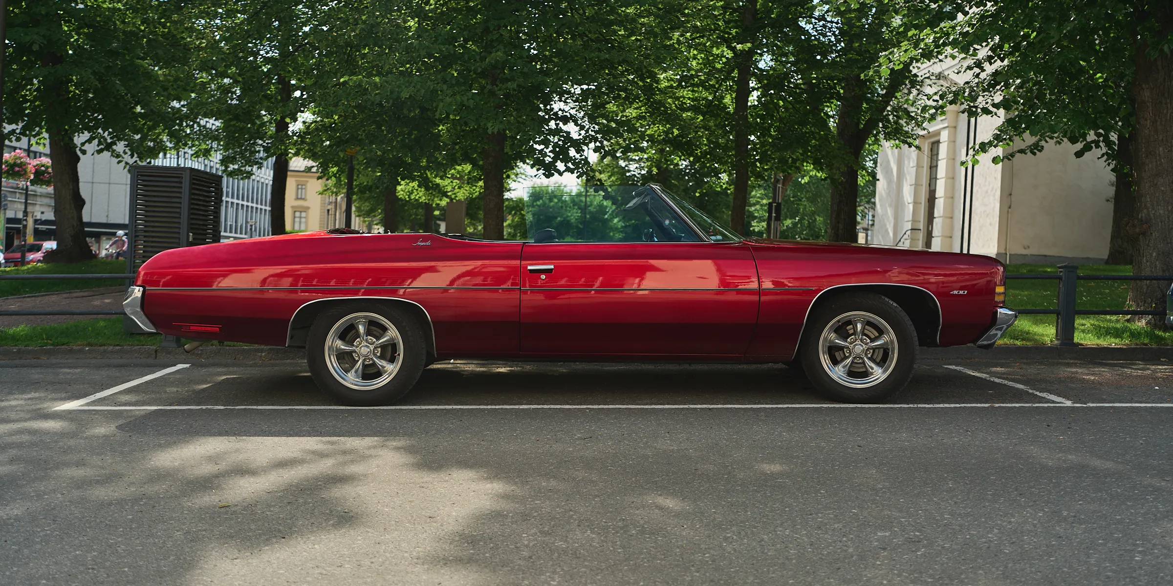 Red vintage convertible at the roadside in front of a green hedge