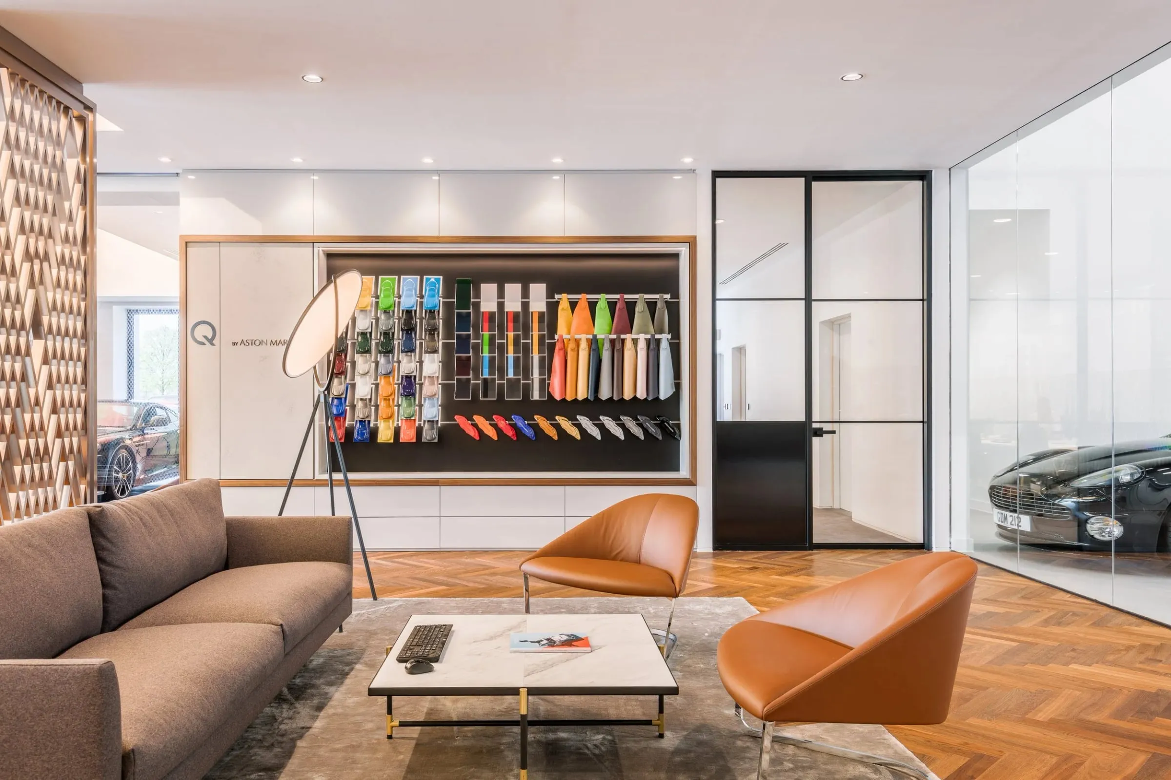 Innenraum-Lounge mit Sofa, zwei Ledersesseln und Marmortisch, an der Wand farbige Material- und Lackmuster