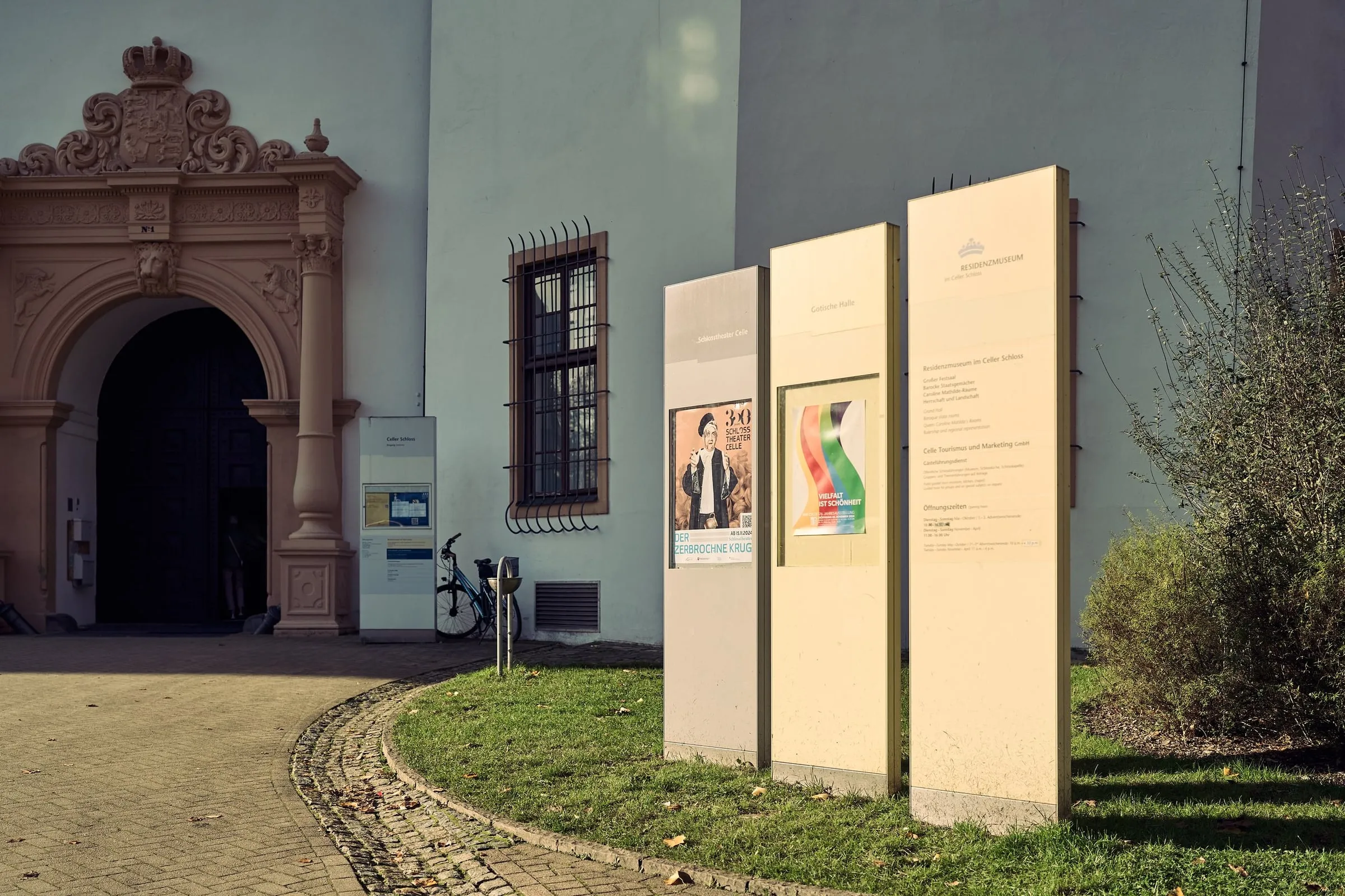 Historisches Eingangsportal eines Museums mit Plakatstelen und Informationstafeln im Hof