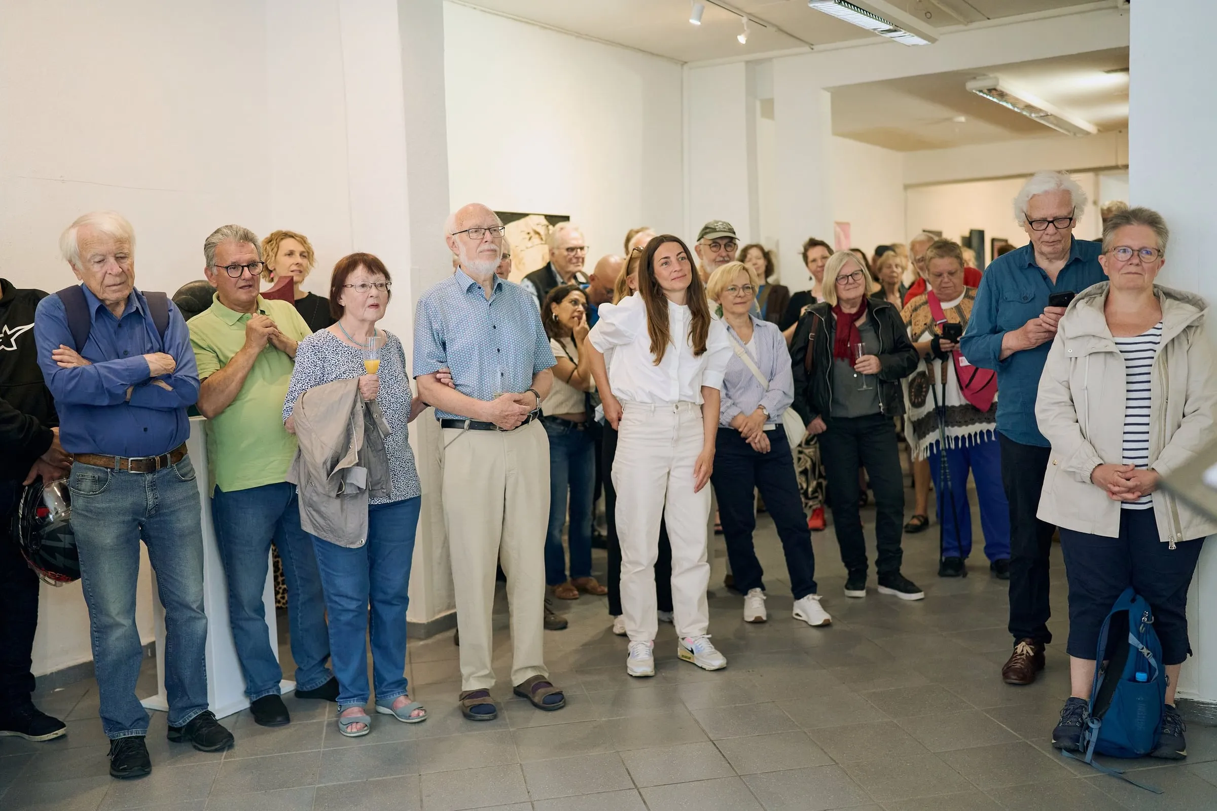 Publikum steht dicht beieinander im Ausstellungsraum und folgt der Eröffnung