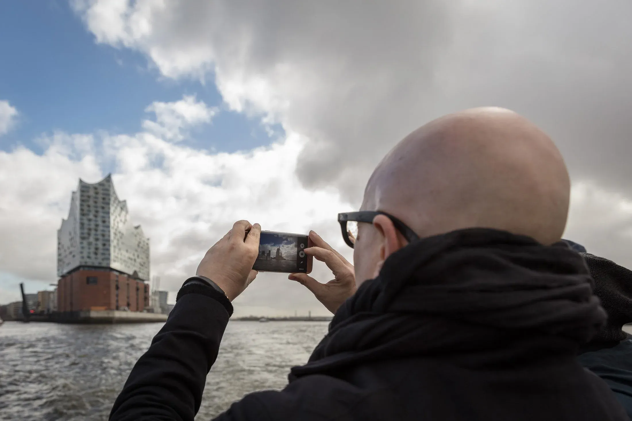 Teilnehmer fotografiert die Elbphilharmonie mit dem Smartphone vom Wasser aus