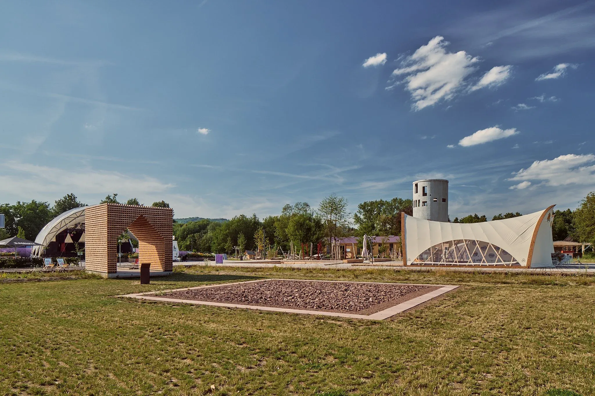 Gelände der Landesgartenschau Höxter mit Backsteinpavillon, geschwungenem Holzbau und Aussichtsturm unter Wolken