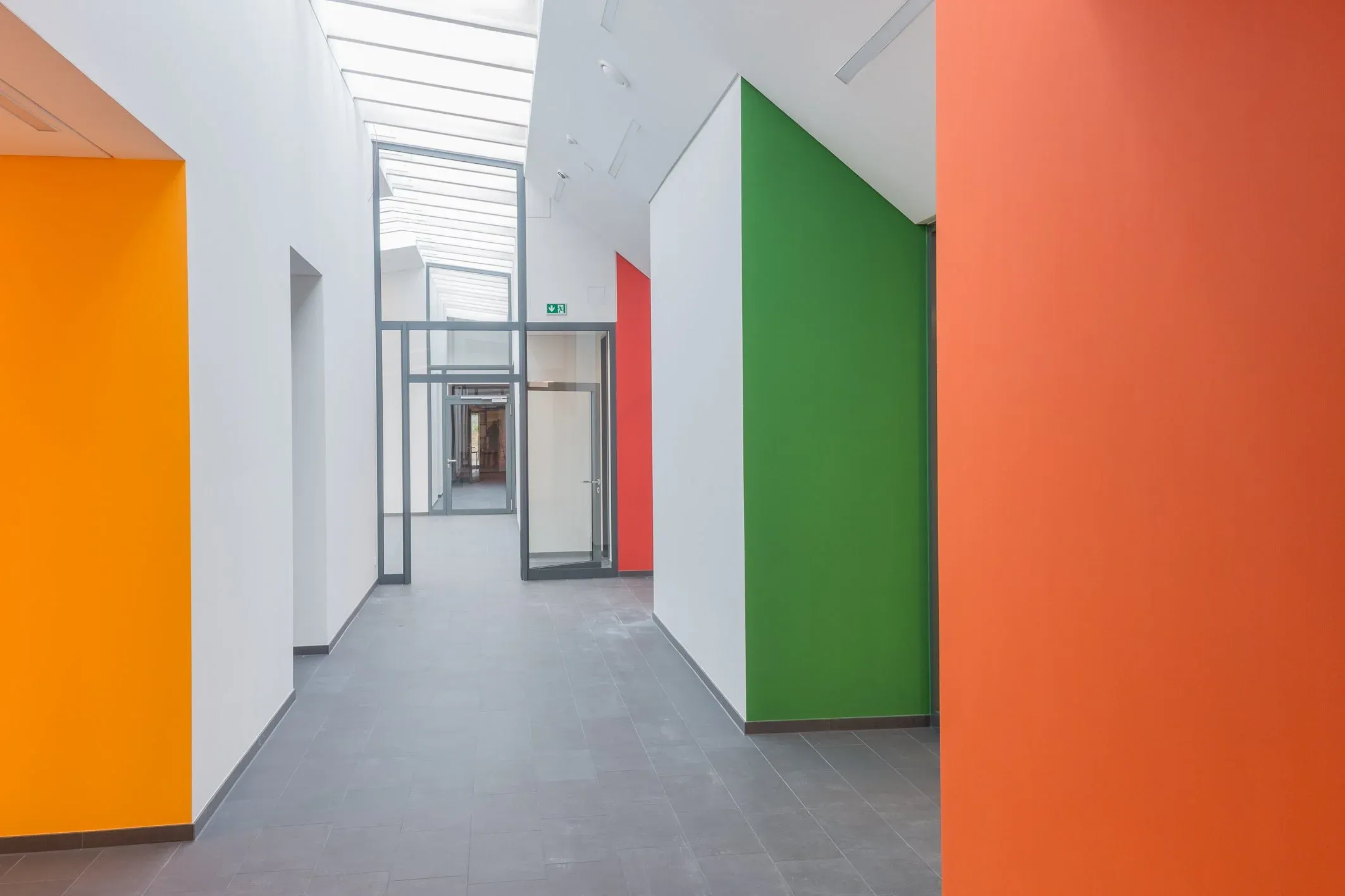Innenaufnahme eines Flurs mit Oberlicht und farbigen Wandflächen in Orange, Rot und Grün