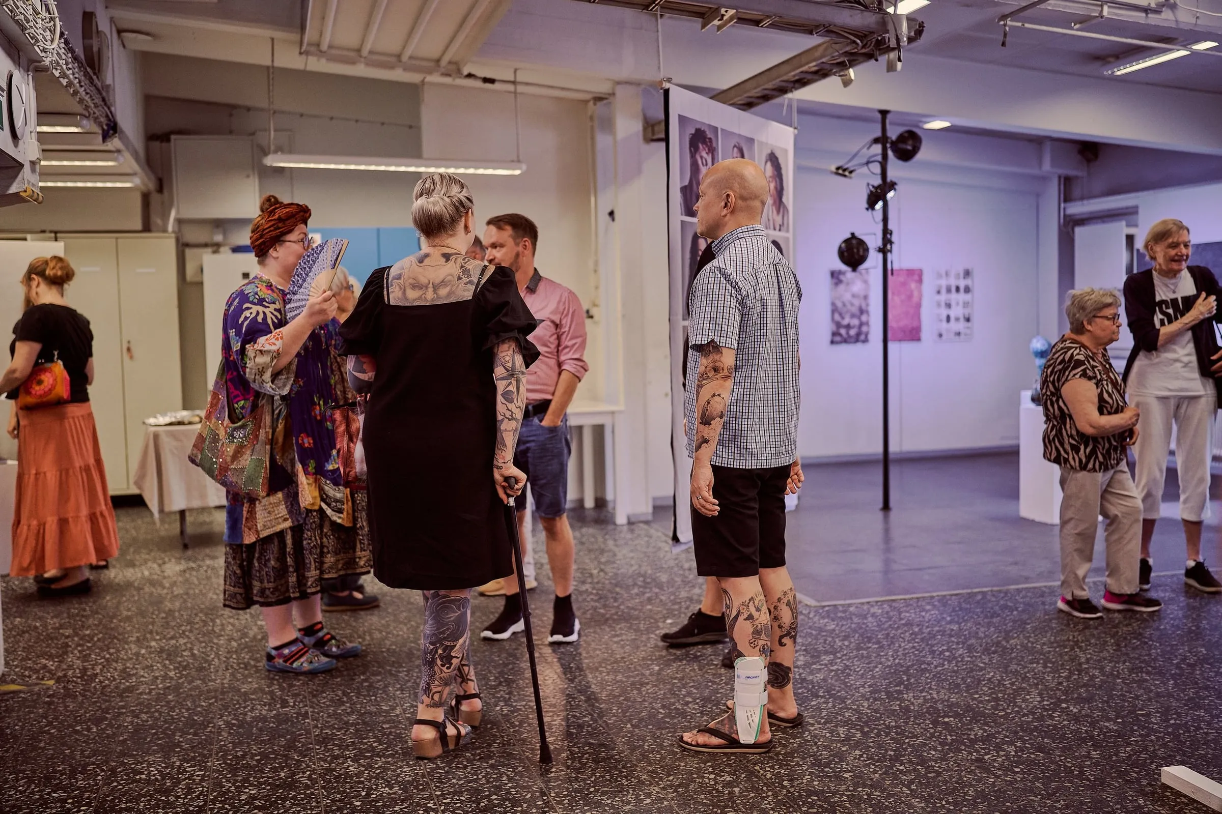 Besucherinnen und Besucher stehen in Gruppen im Ausstellungsraum zwischen Stellwänden mit Werken
