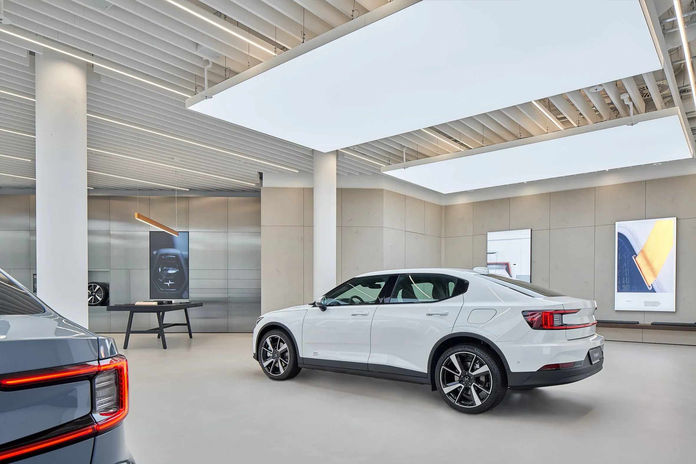 Innenraum des Showrooms, weißer Polestar 2 in Seitenansicht unter heller Lichtdecke zwischen Säulen