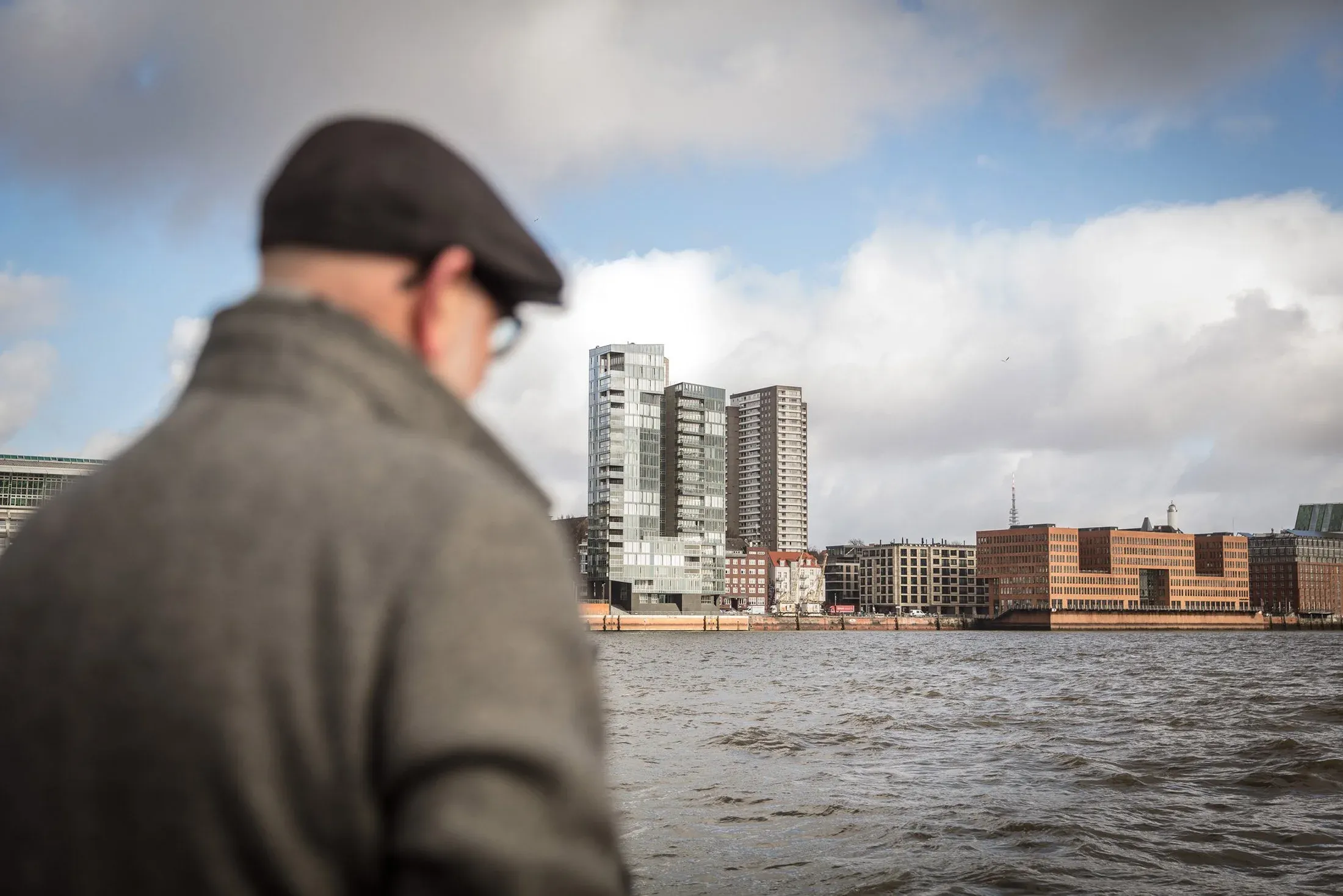 Teilnehmer im Vordergrund blickt über die Elbe auf die Bebauung am gegenüberliegenden Ufer