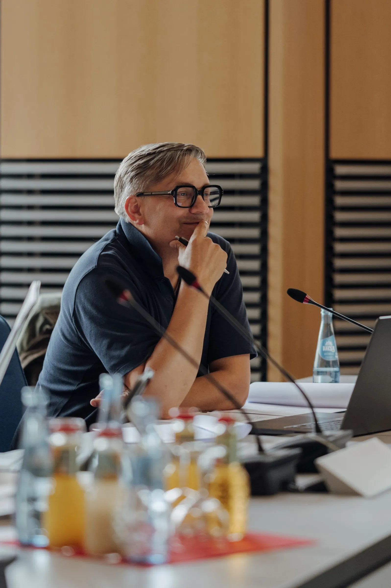 Roman Thomas smiling at the session table, hand on his chin, water and juice bottles in the foreground