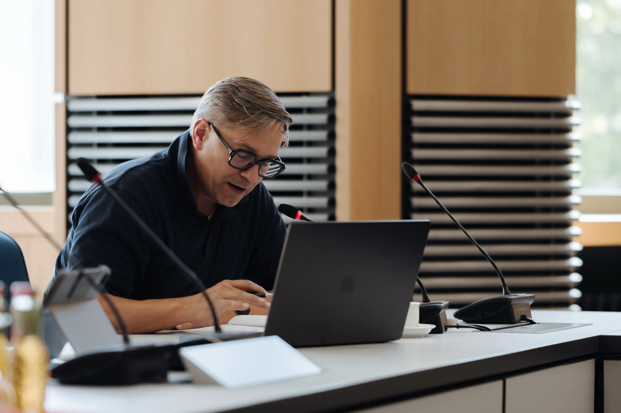 Roman Thomas working on a laptop at the session table, microphones in front of him