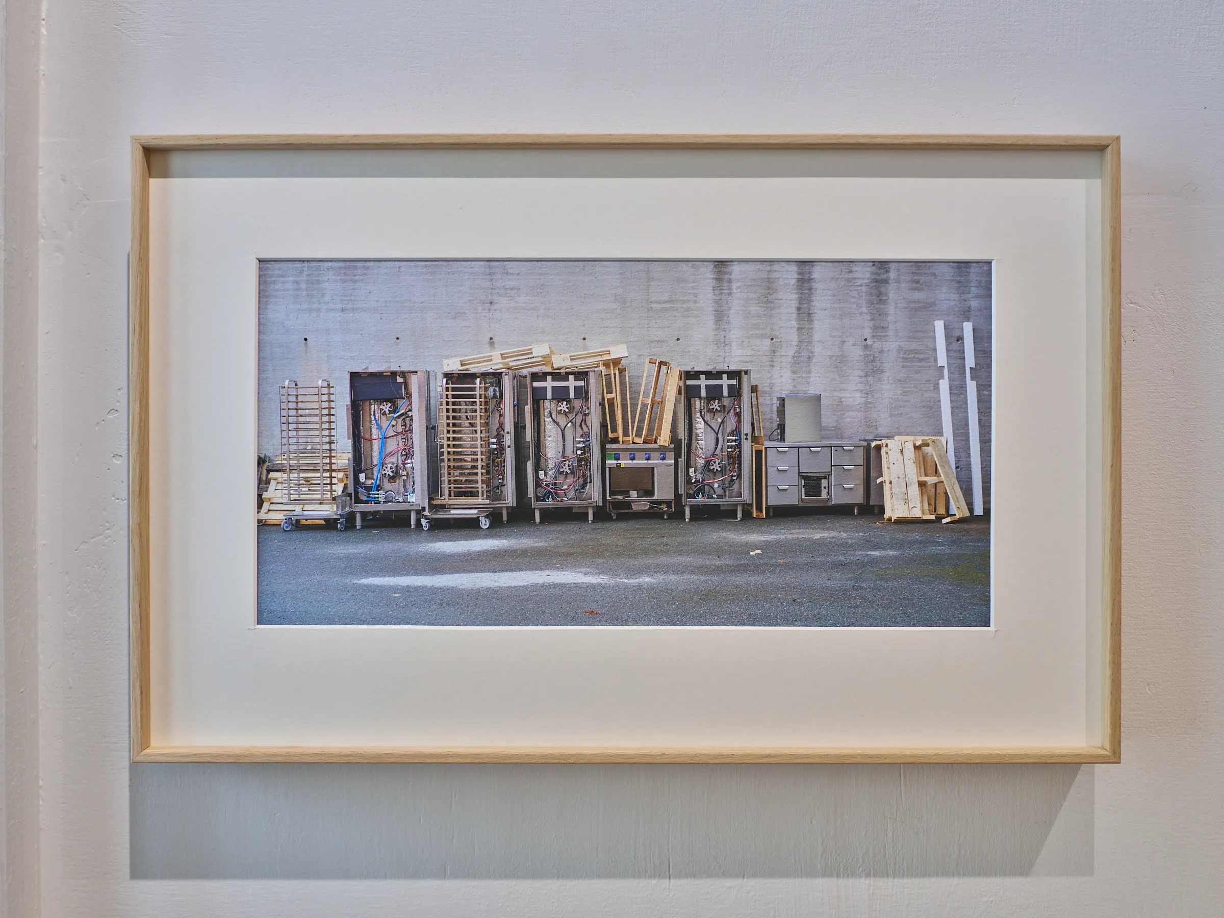 Widely framed photograph of a row of industrial trolleys in front of a concrete wall