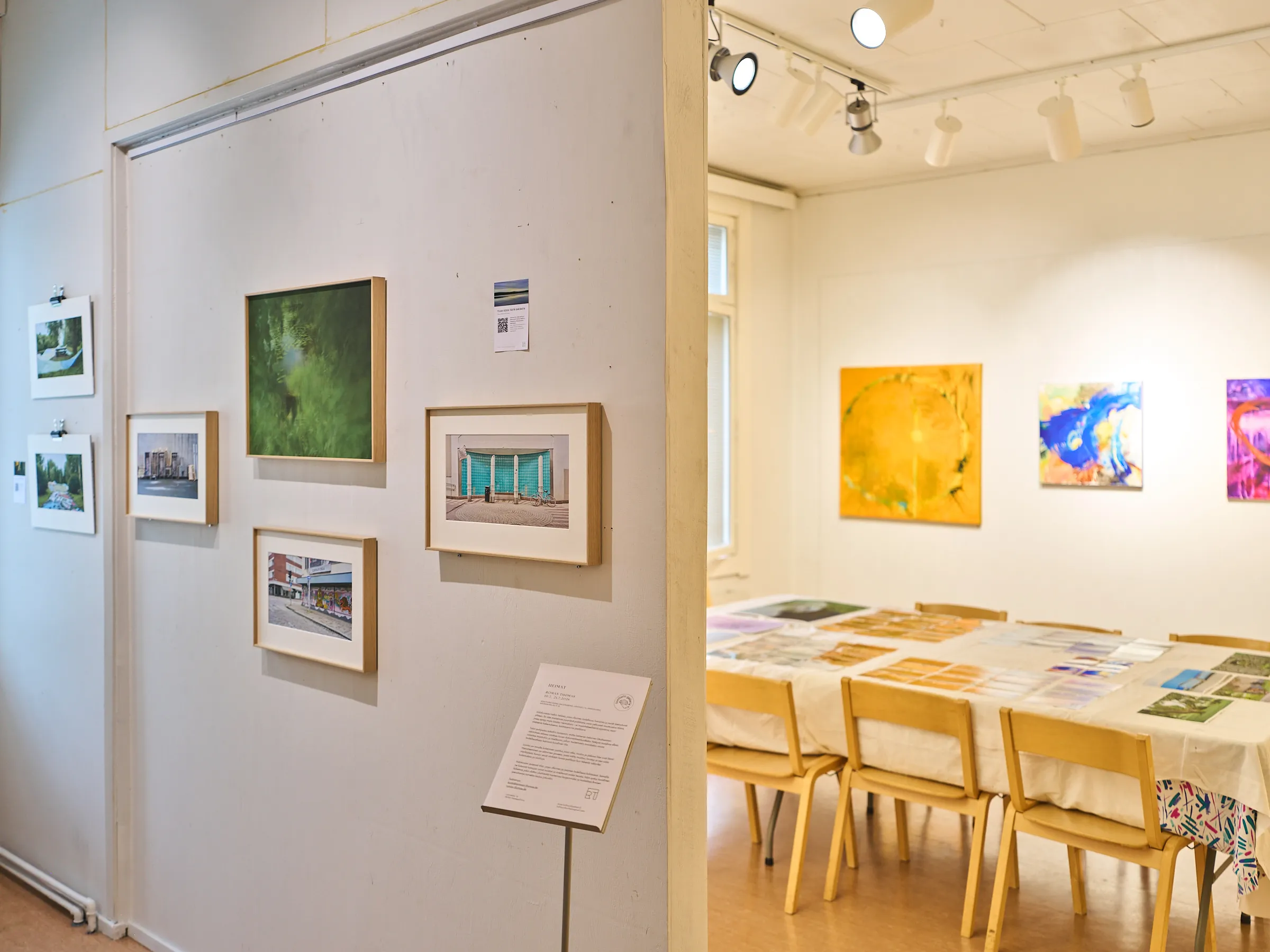 Two walls at an angle, framed photographs on the left, the open bright room on the right
