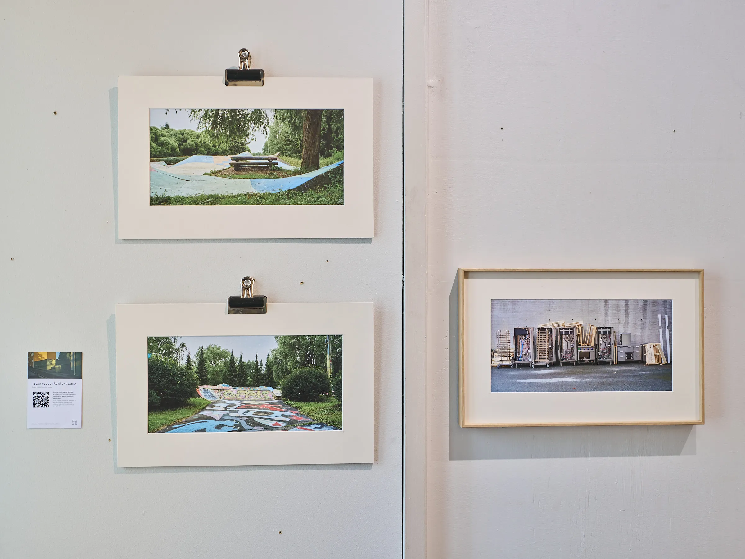 Two photographs hung with clips on a bright wall, a framed picture to the right