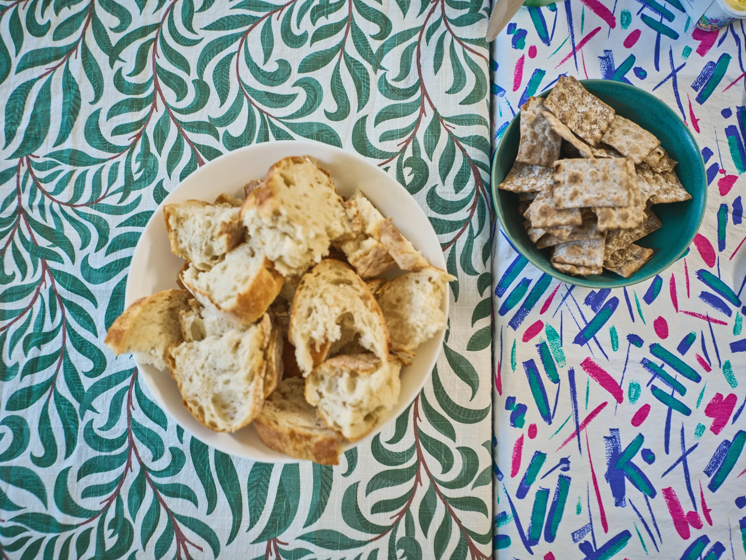 White bowl with pieces of light bread seen from above on a green patterned cloth