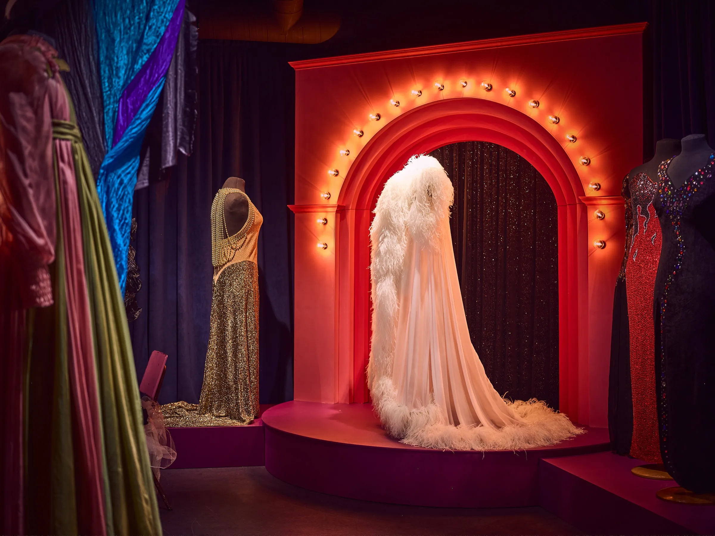 Exhibition room at Museo Skogster with an illuminated stage arch and sparkling stage costumes on mannequins