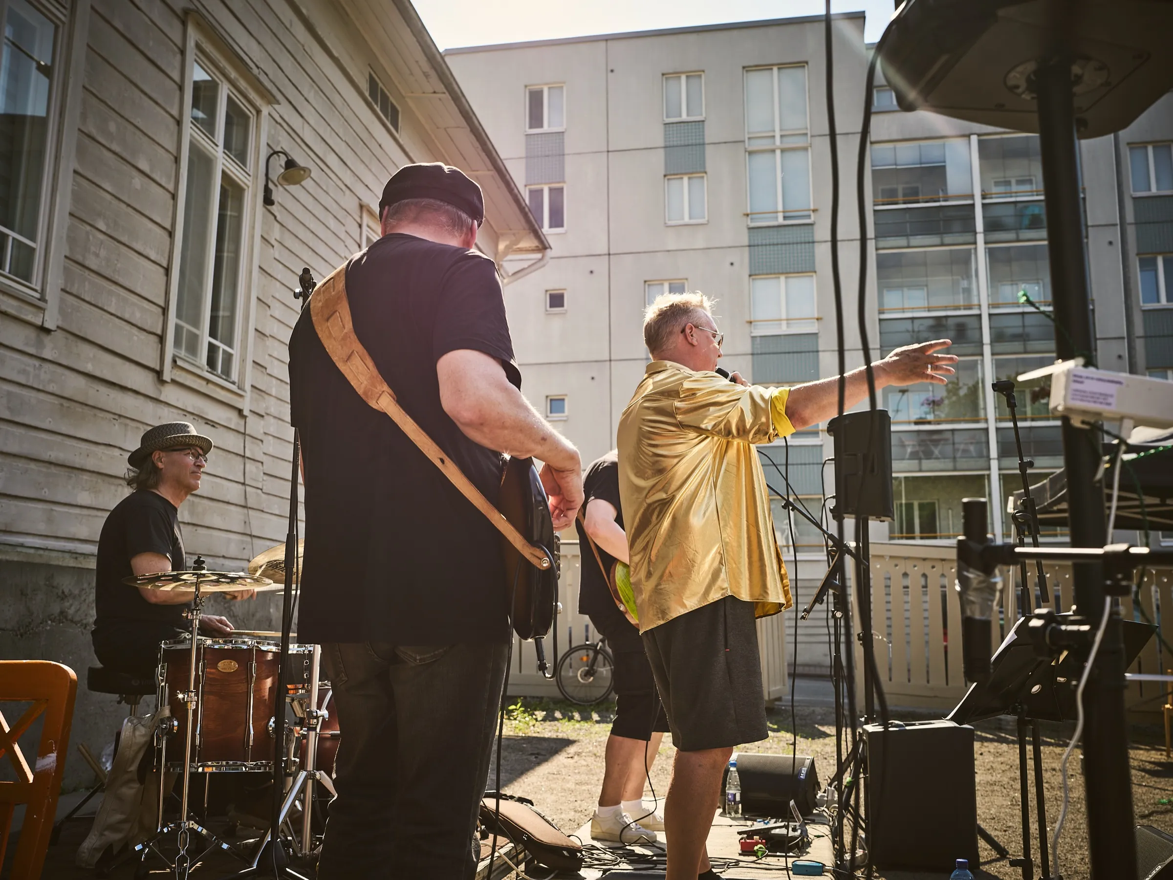 View from behind the stage: drummer, guitarist and the singer in the golden shirt