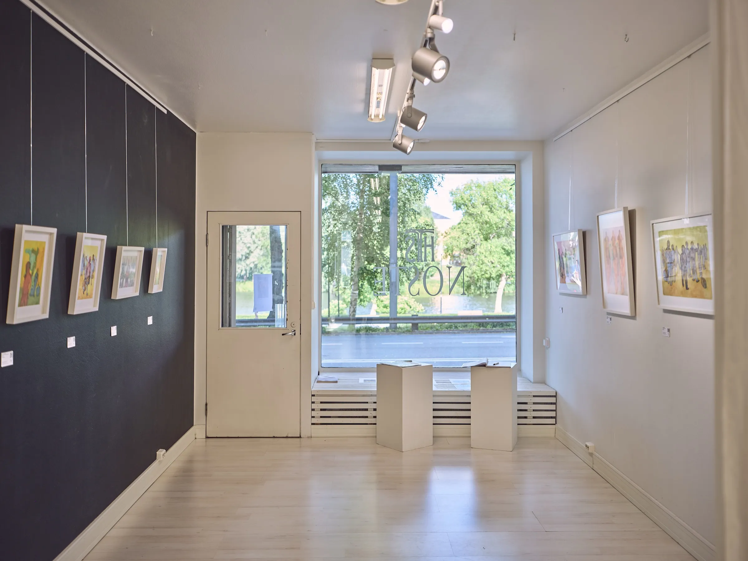 Gallery room with a dark and a light wall, the large window to the street in the middle
