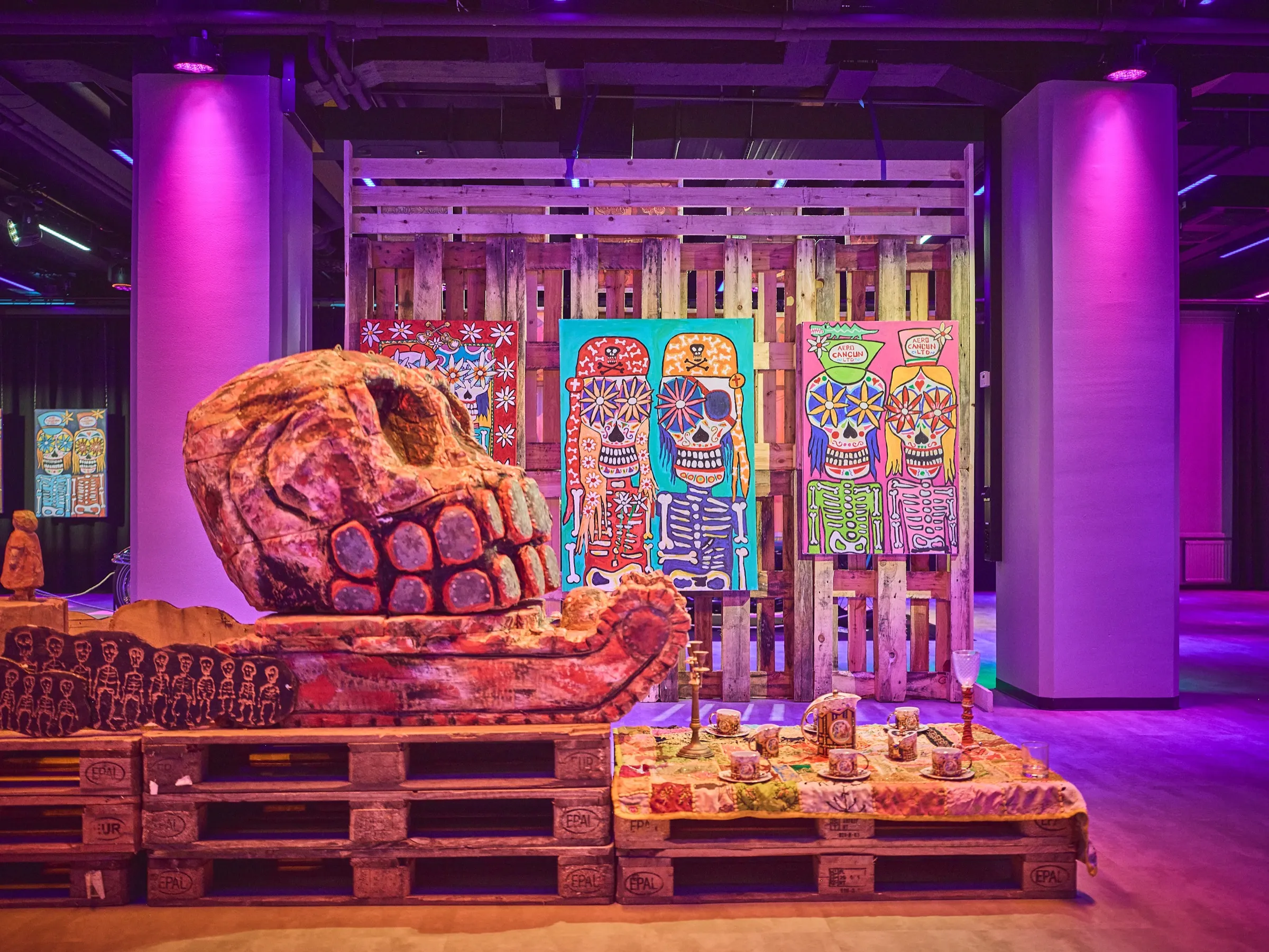 Large carved skull on pallets, brightly painted panels behind it