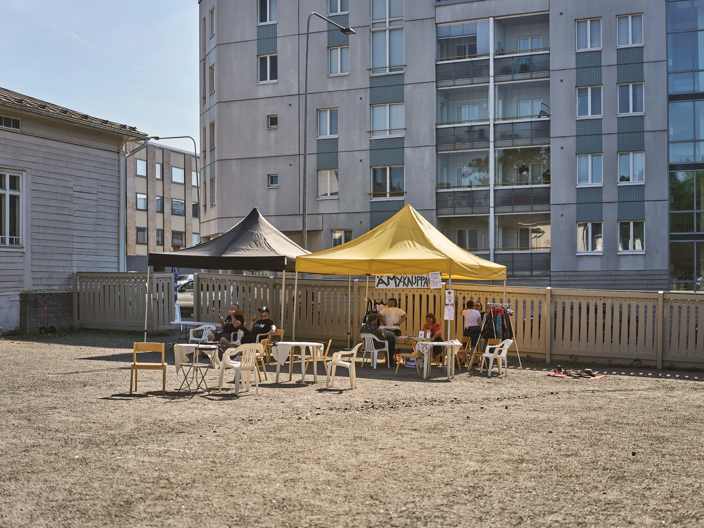 Courtyard at Ämykesä with tents, flea market stalls and an apartment block behind