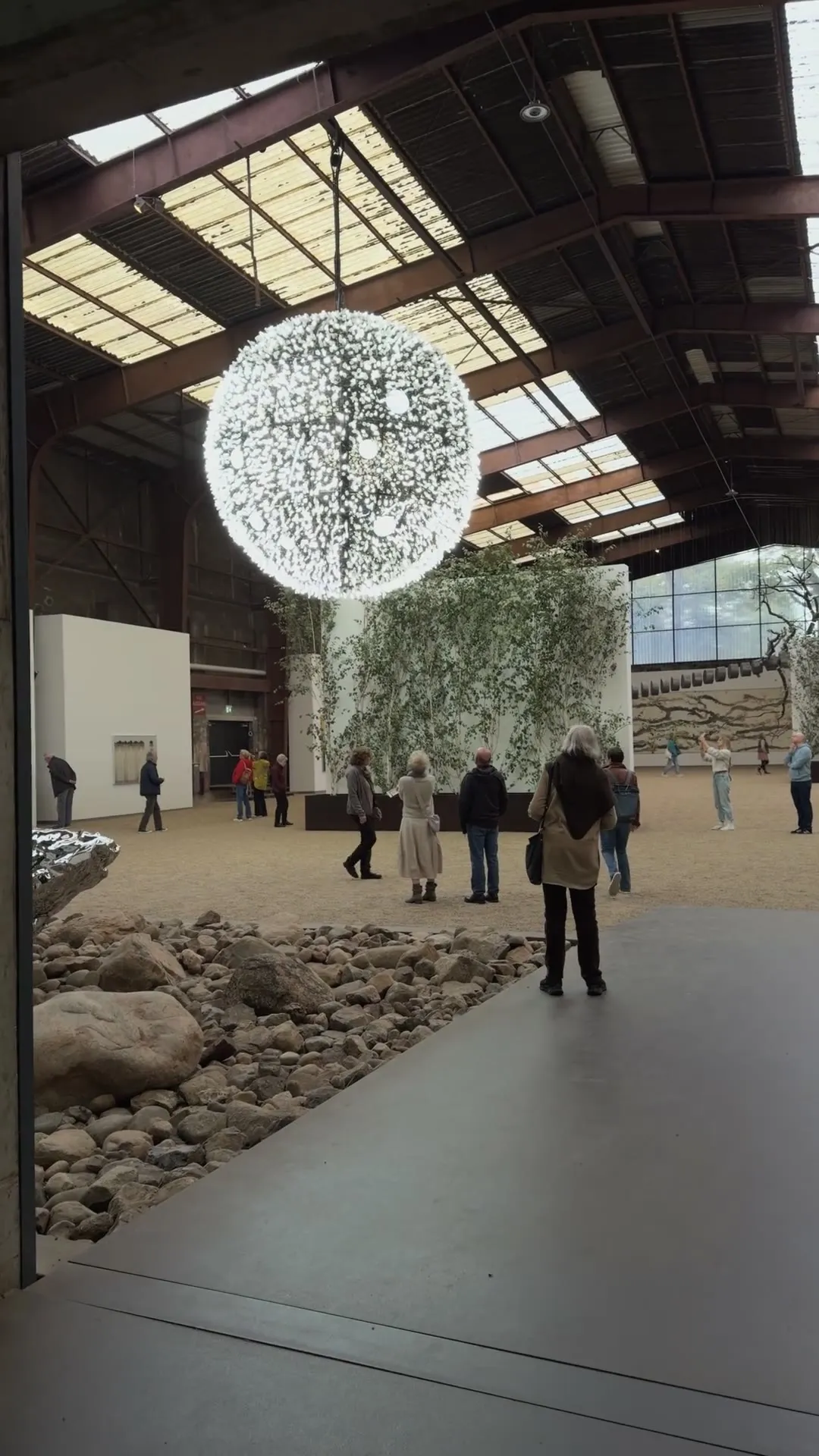 Portrait: the glowing sphere under the hall roof, visitors below