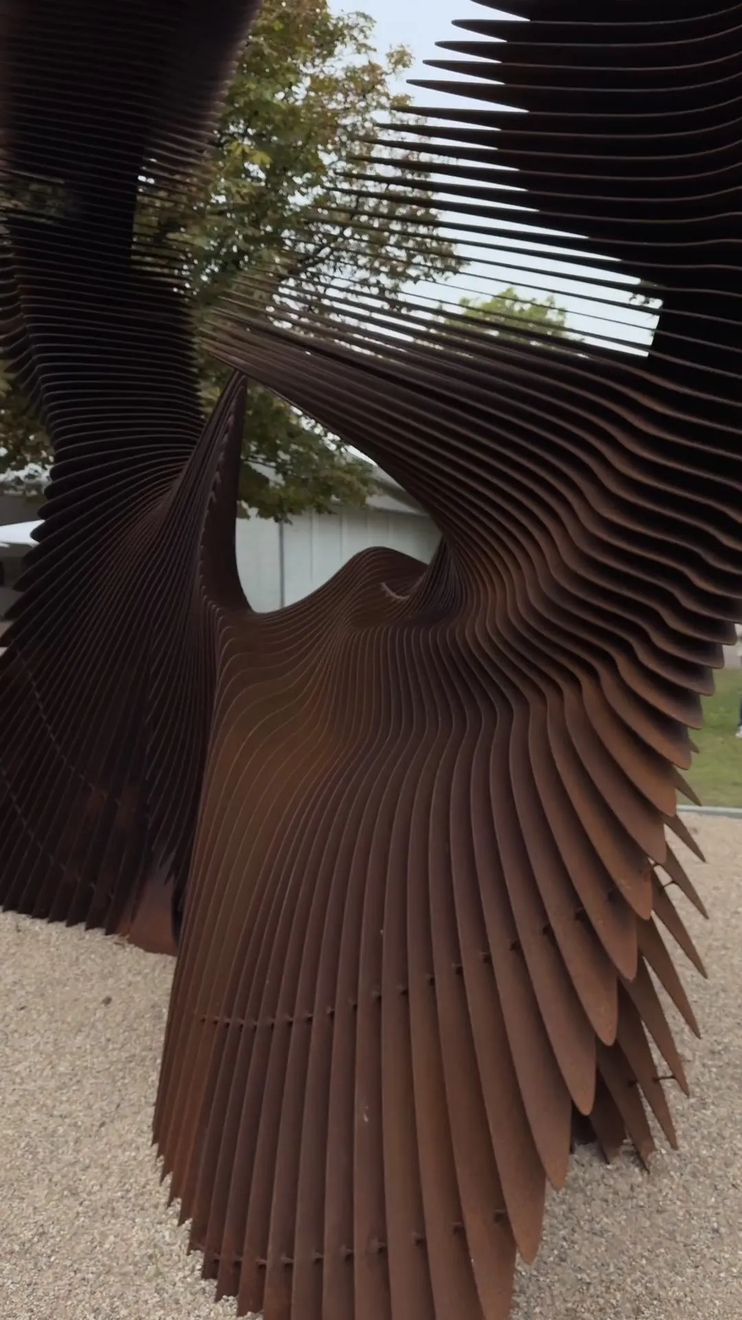 The camera glides close along the steel slats of the same sculpture