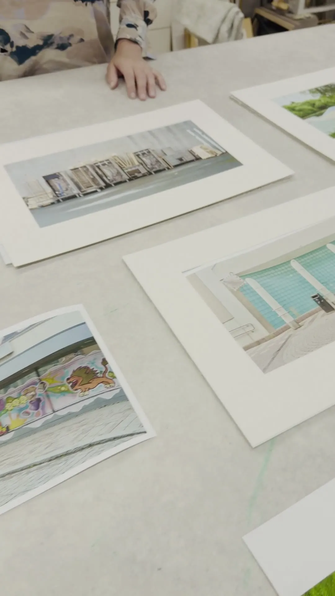 Video: view across the workshop table with prints laid out, work going on in the background