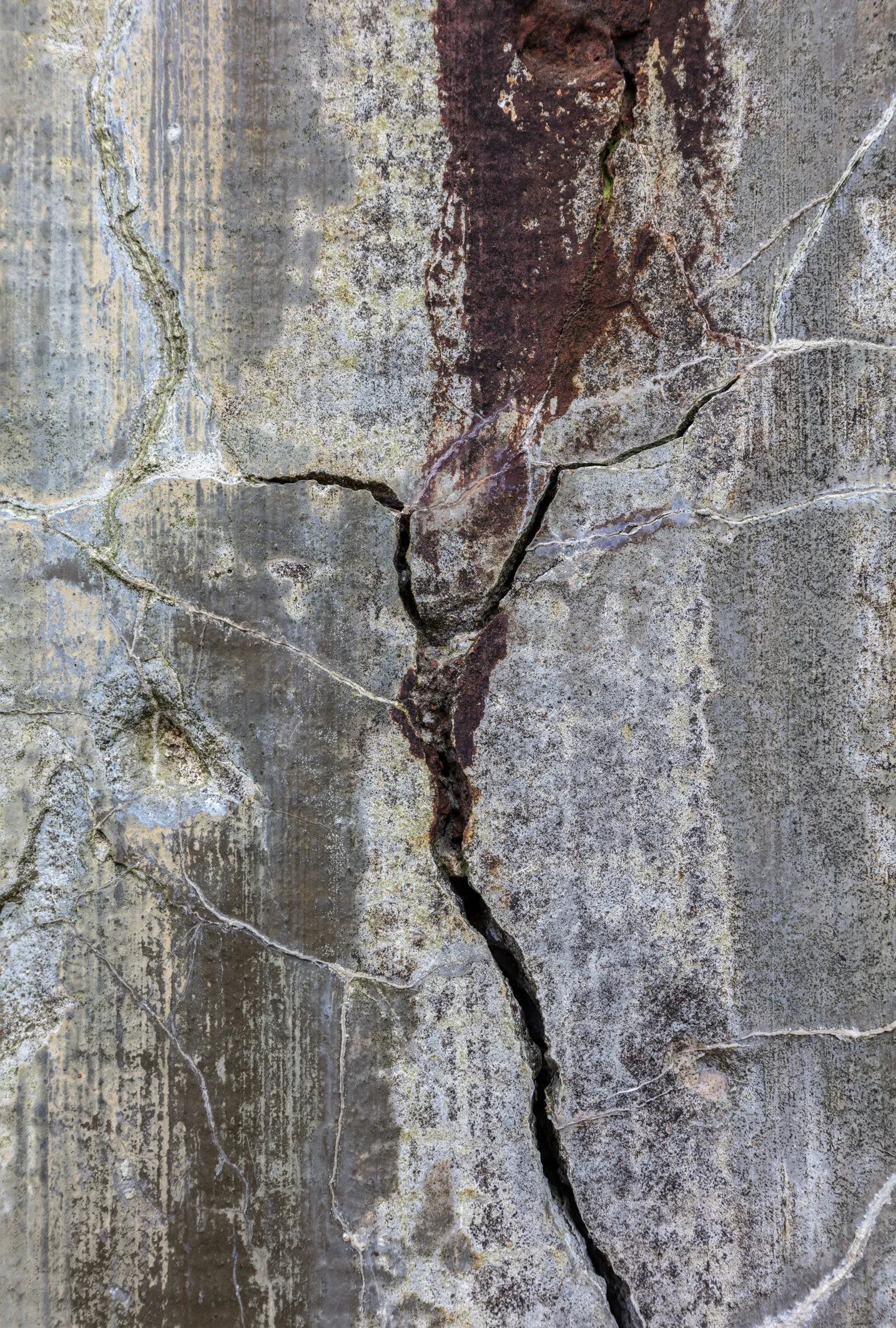 Grauer Beton mit senkrechtem dunkelrotem Streifen und einem durchgehenden vertikalen Riss, helle Schlieren