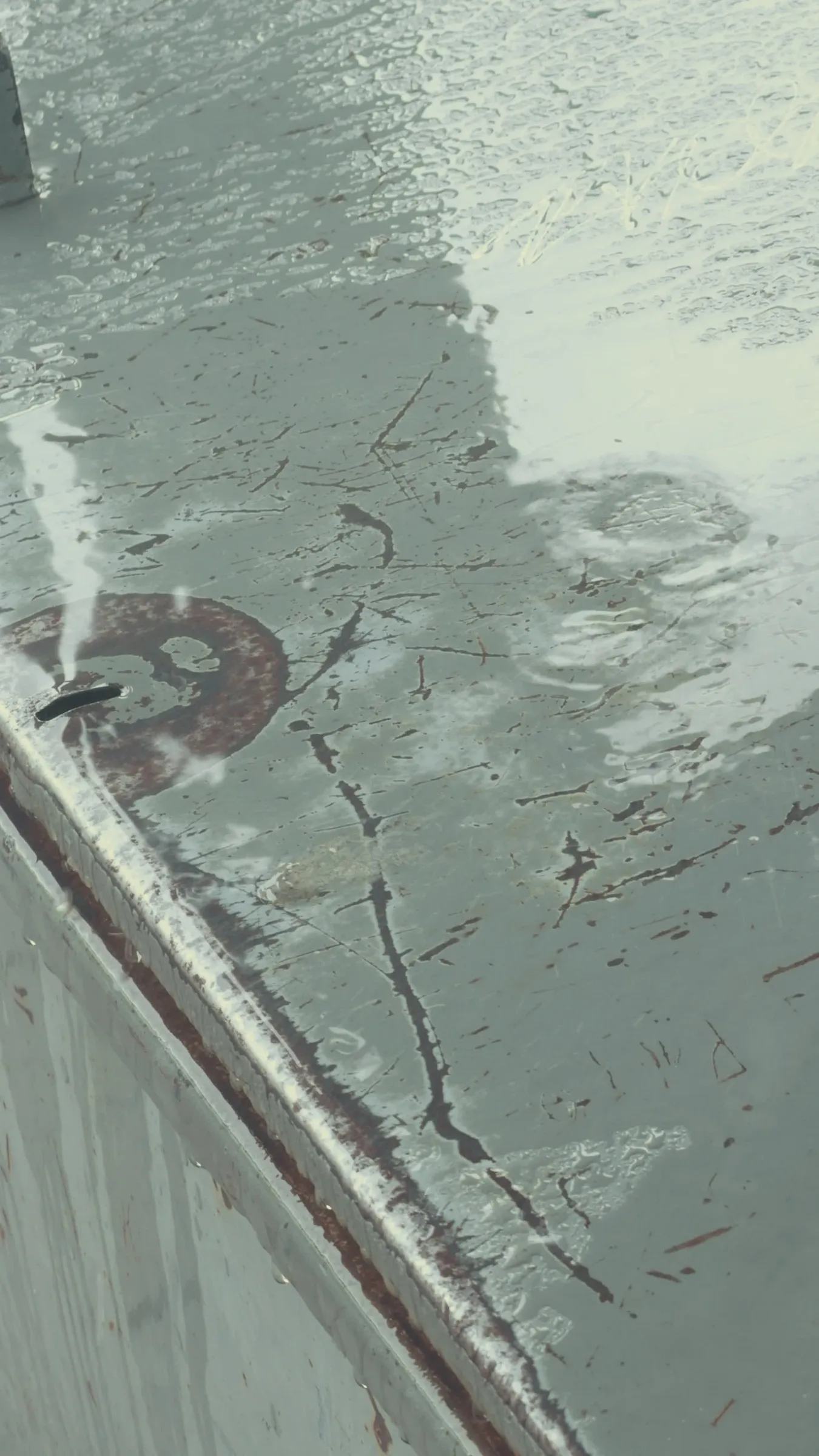 Raindrops gathering on a scratched metal surface