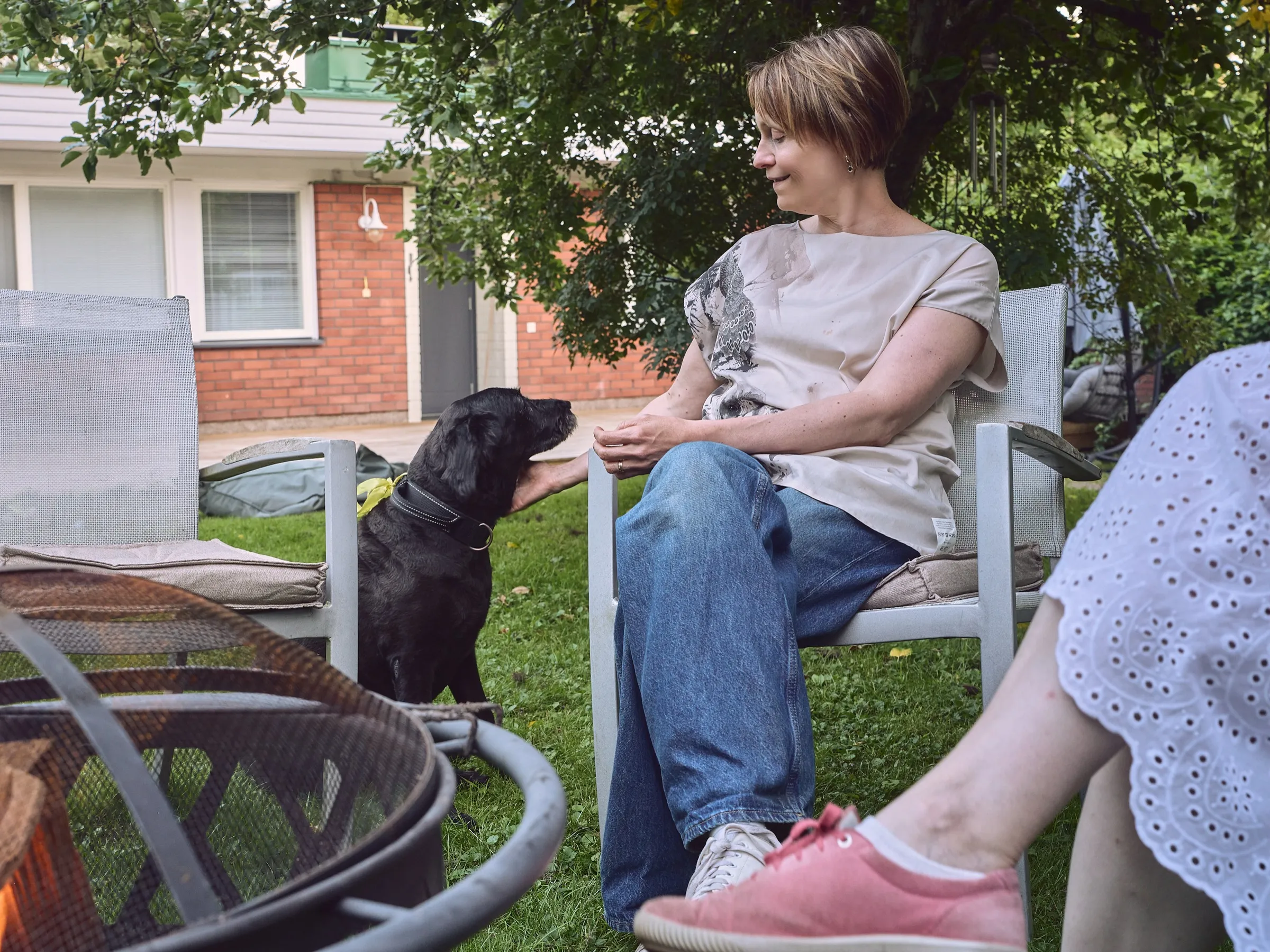 Woman at the edge of the fire bowl in conversation, a dog looking up at her
