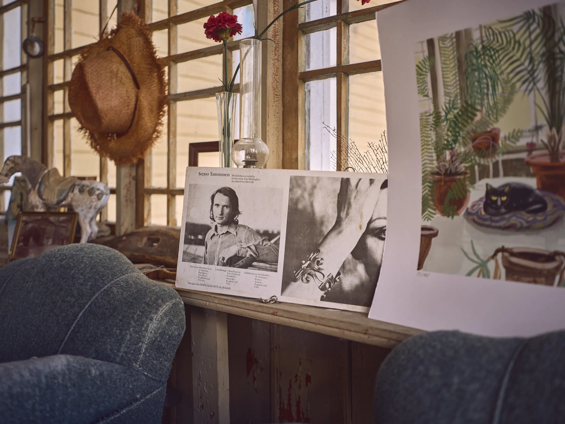 Old armchairs by the lattice window, a black and white portrait and a watercolour with a cat between them