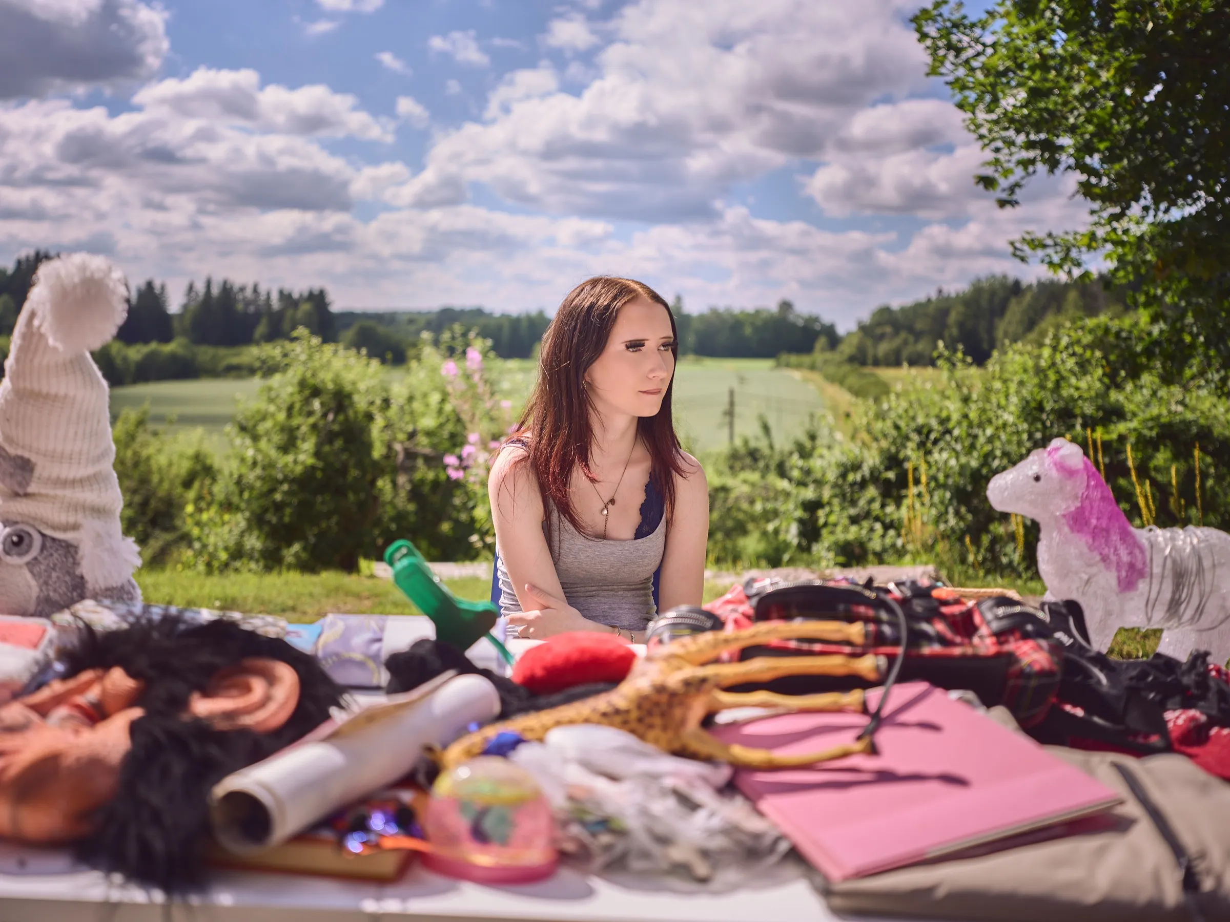 Woman behind a colourful flea market stall, fields and a wide sky behind