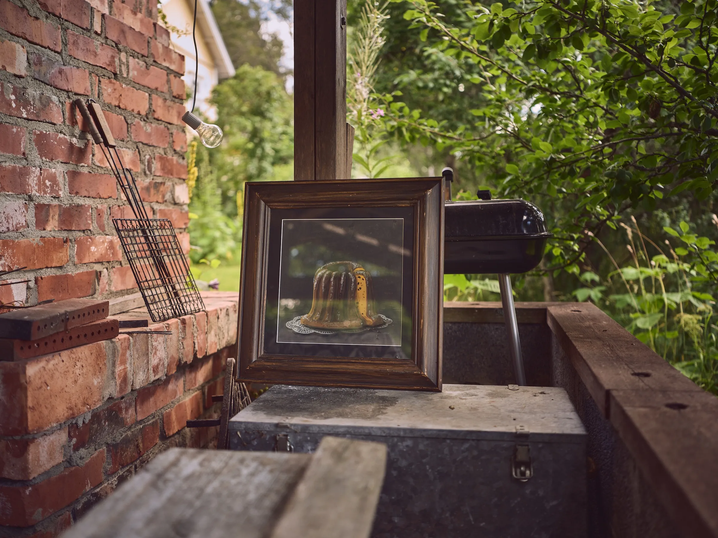 Small framed still life leaning against a brick wall in the garden