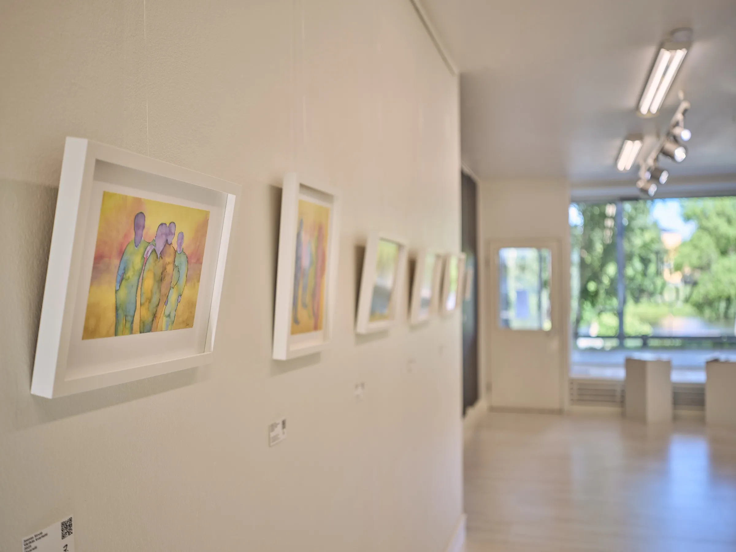Row of watercolours at an angle in the light, view towards the gallery window