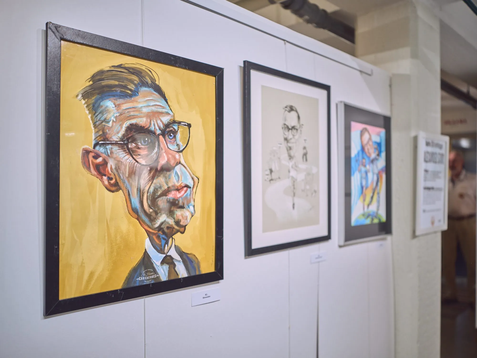 A boldly painted caricature portrait on a yellow ground, beside a fine ink drawing