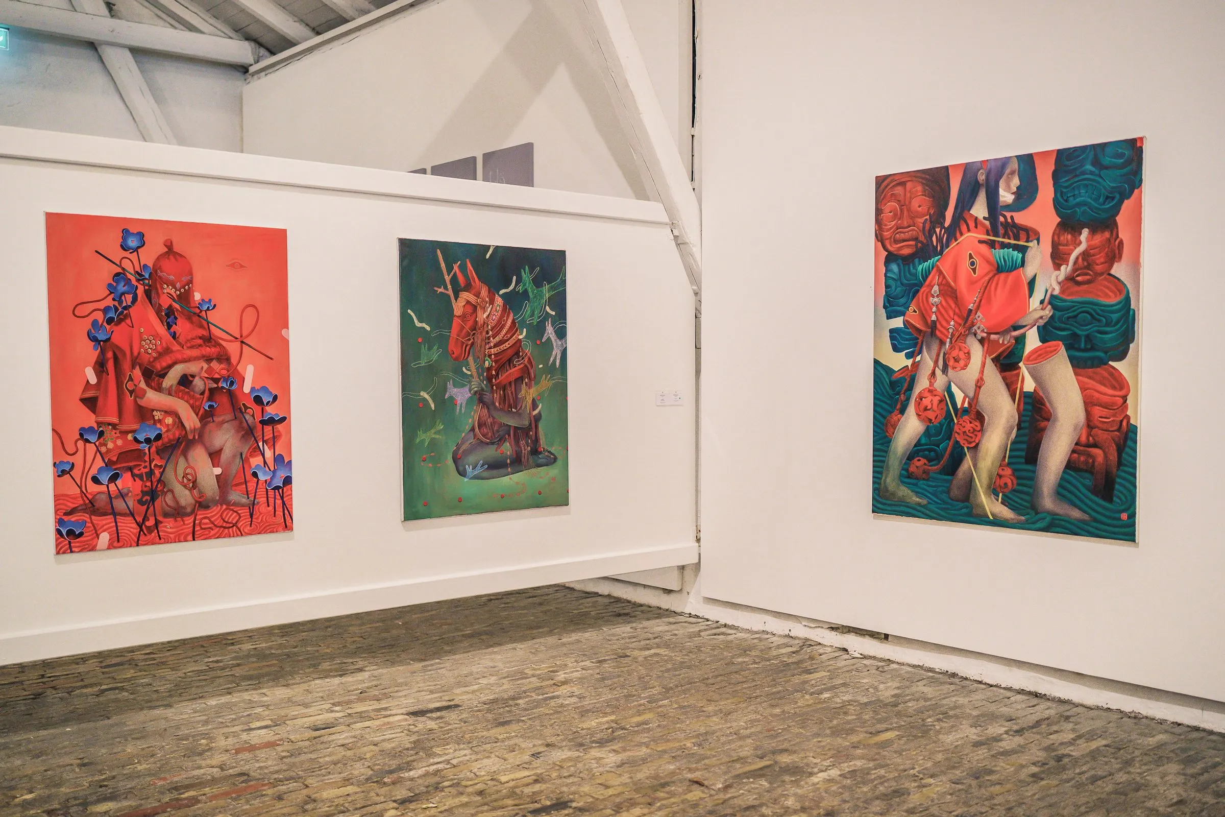 Three large, colour-intense paintings with figures in red, green and blue on white walls