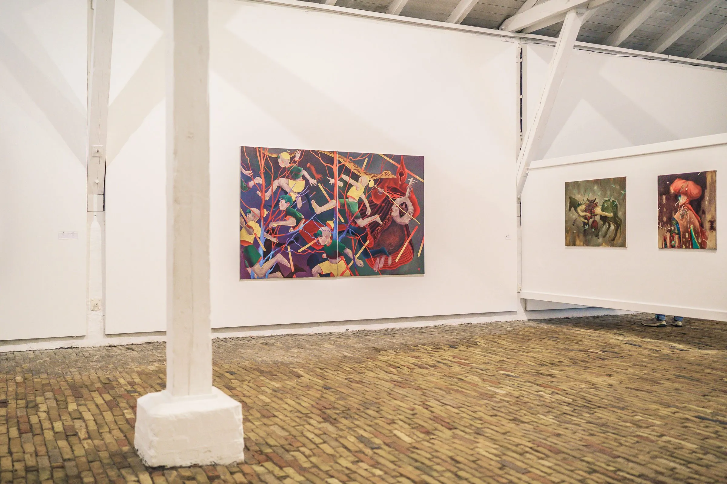 A white pillar in front of a colourful, busy painting, more pictures behind