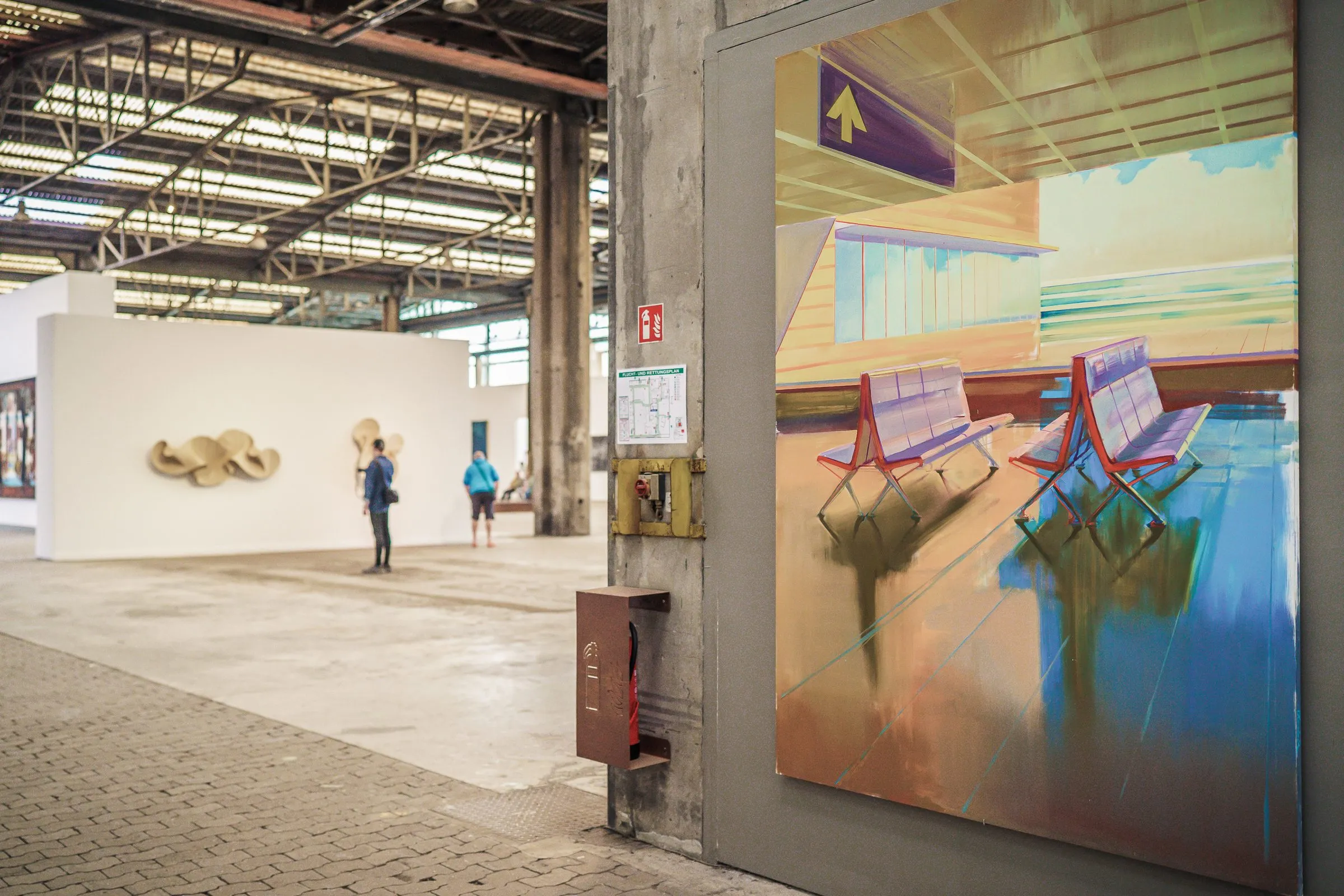 A large painting with empty seats and an arrow, beside it a view into the long hall